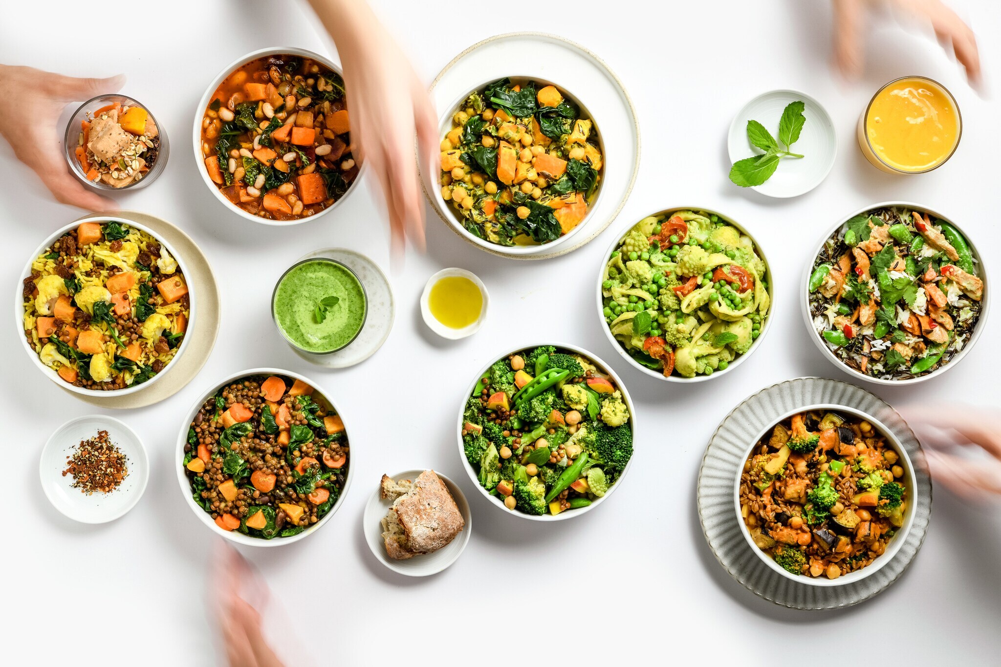 Mehrere Schüsseln mit Gemüse auf einem weißen Tisch