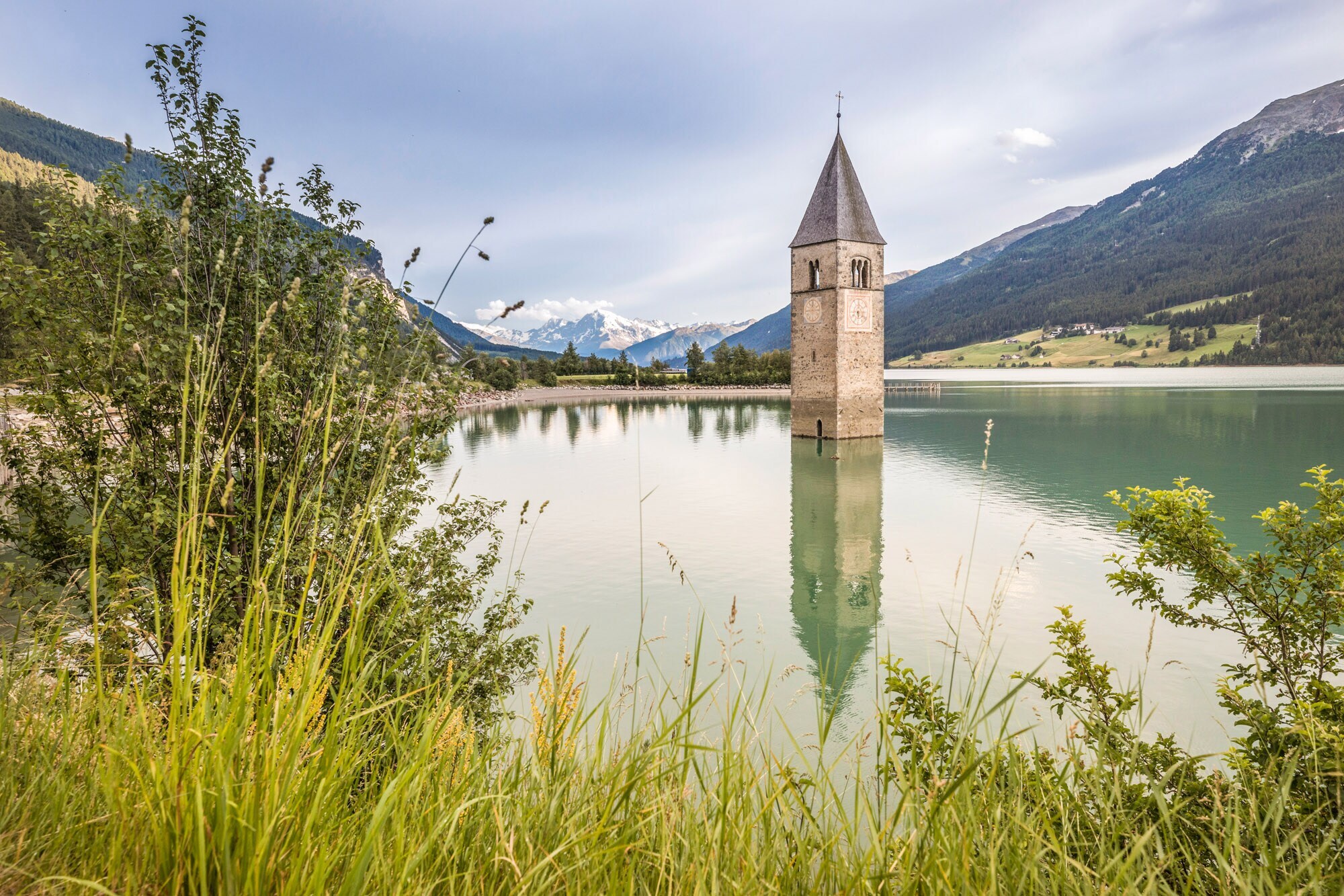 Der Kirchturm im Reschensee mit Bergen im Hintergrund