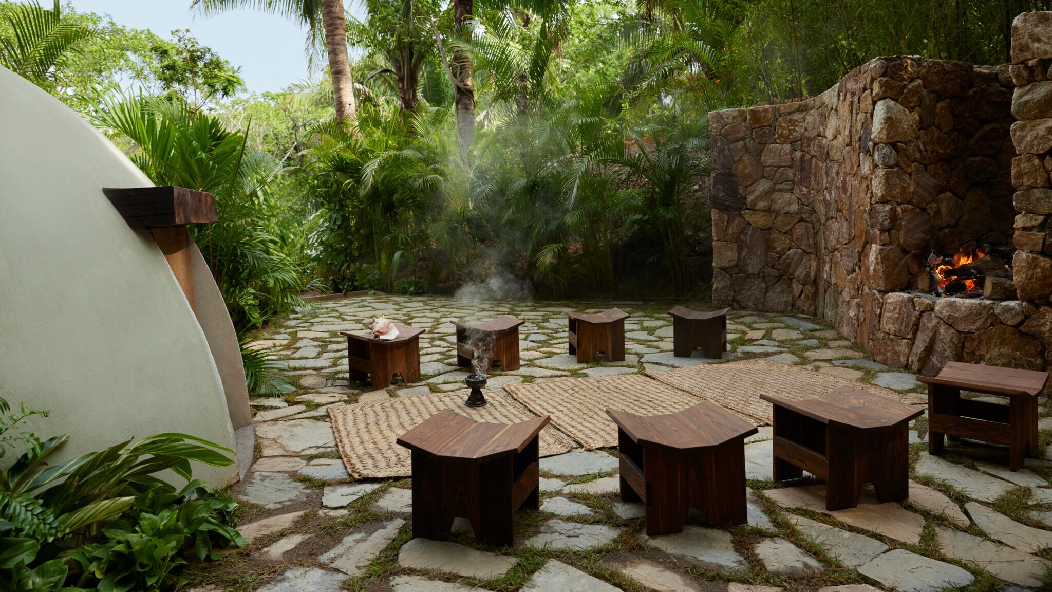 Steinplatz mitten im Dschungel mit Feuerstelle und Holzhockern