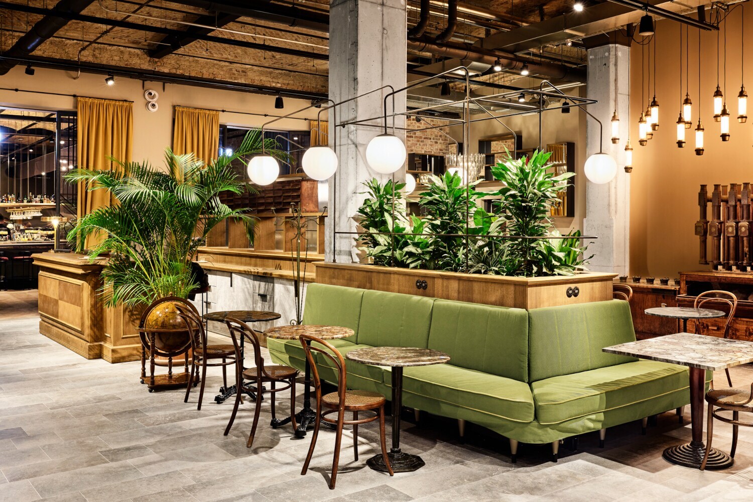 Geräumige Lobby des Berliner Hotels im Telepgraphenamt mit grünem Loungebereich und braunen Designstühlen