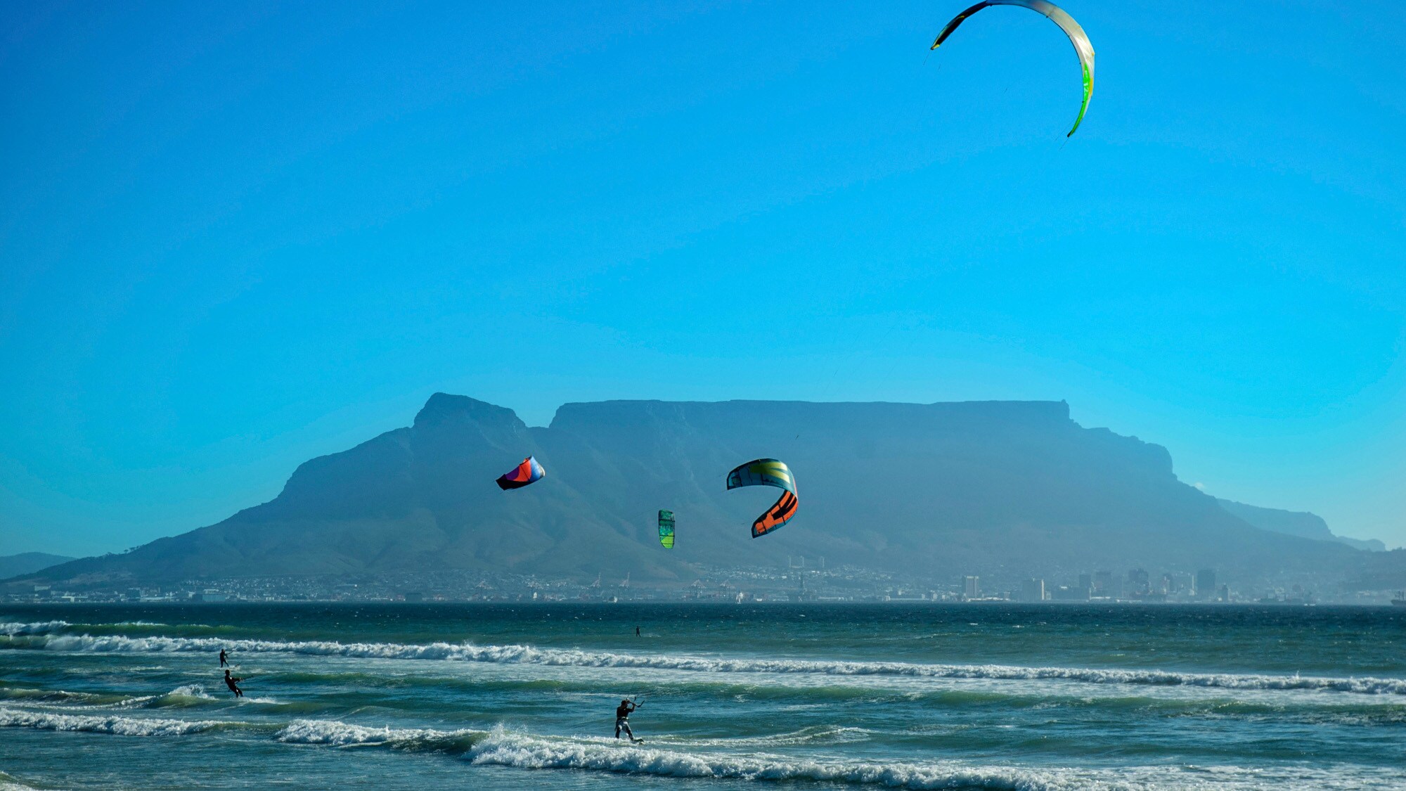 Kitesurfer im Meer, im Hintergrund Kapstadt am Fuße des Tafelbergs Kitesurfer im Meer, im Hintergrund Kapstadt am Fuße des Tafelbergs