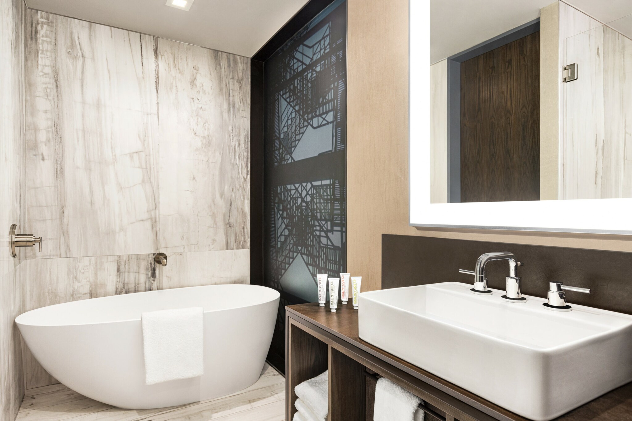 Hotelbad mit weißer, freistehender Wanne, weißem Wachbecken, und Spiegel