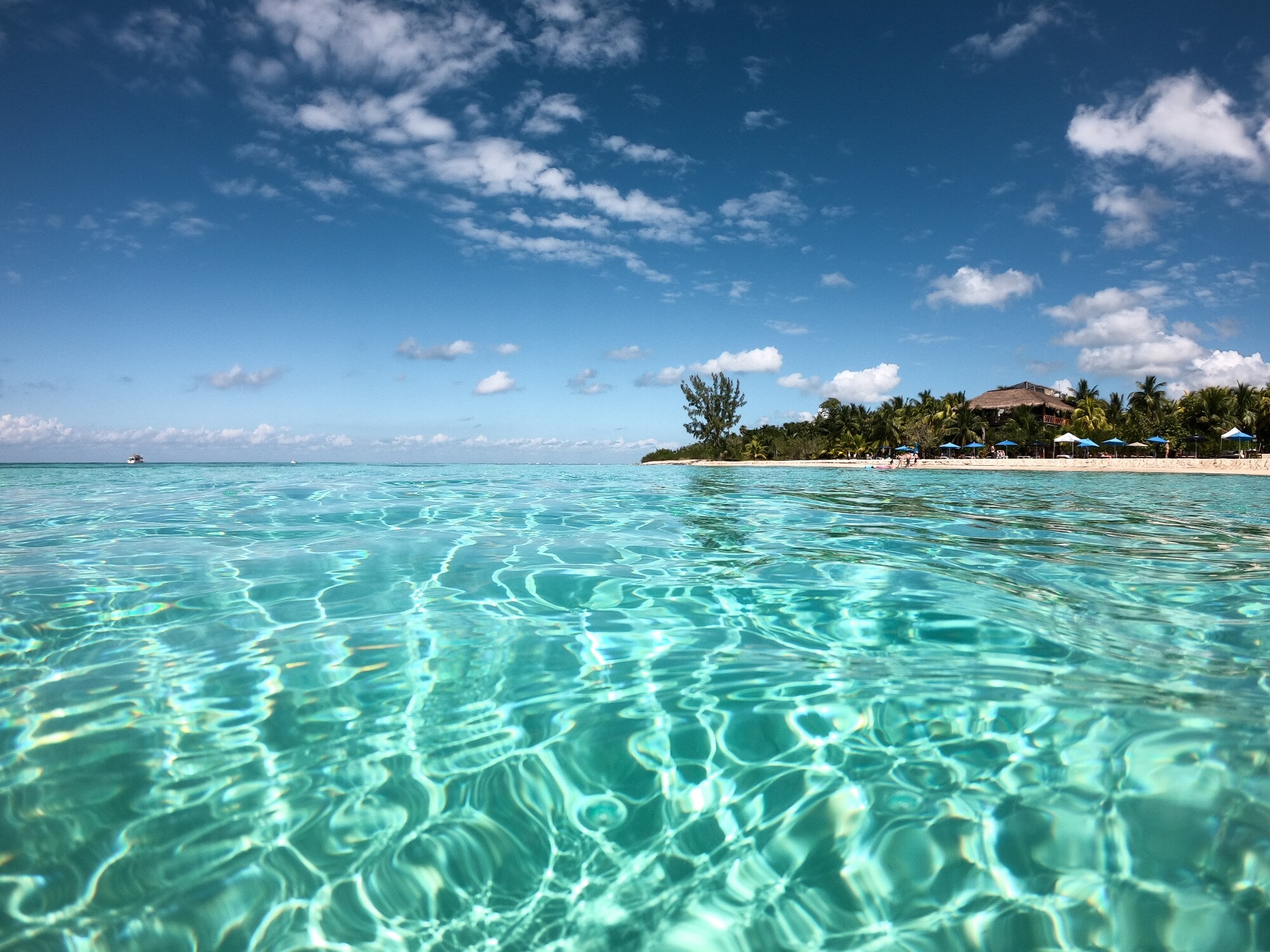 Ein tropischer Strand mit kristallklarem Wasser im Vordergrund Ein tropischer Strand mit kristallklarem Wasser im Vordergrund