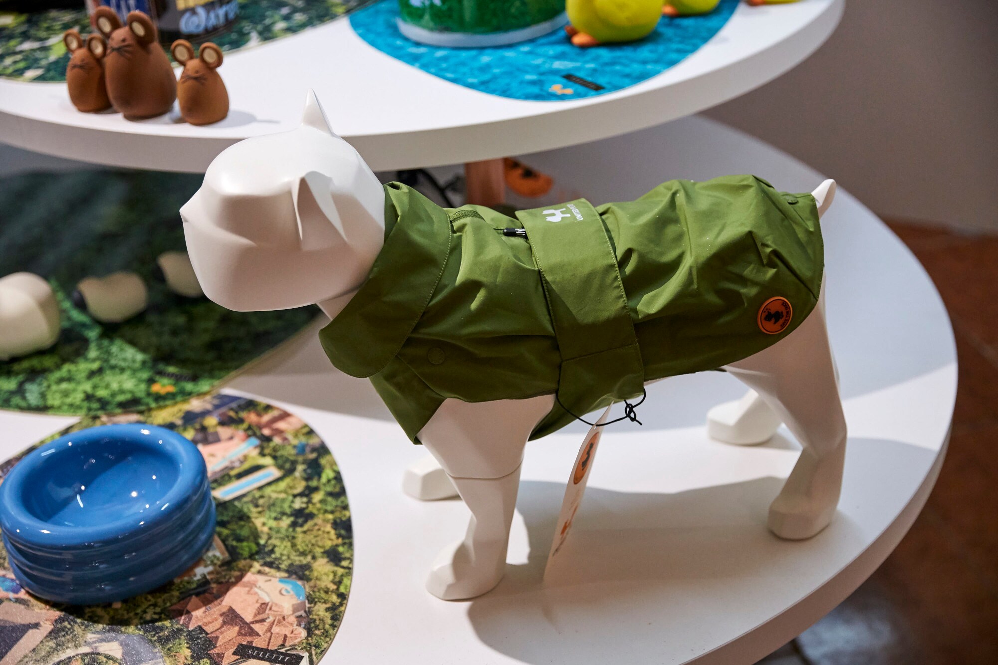 Ein Hundemodell aus Plastik mit einer grünen Regenjacke auf einem Messestand