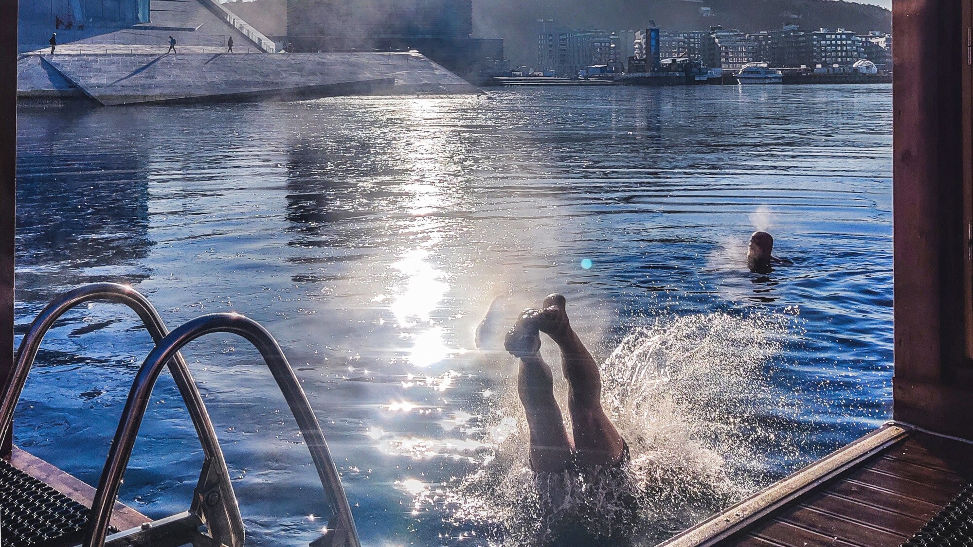 Zwei Personen baden vor einer schwimmenden Sauna im Hafen von Oslo Zwei Personen baden vor einer schwimmenden Sauna im Hafen von Oslo