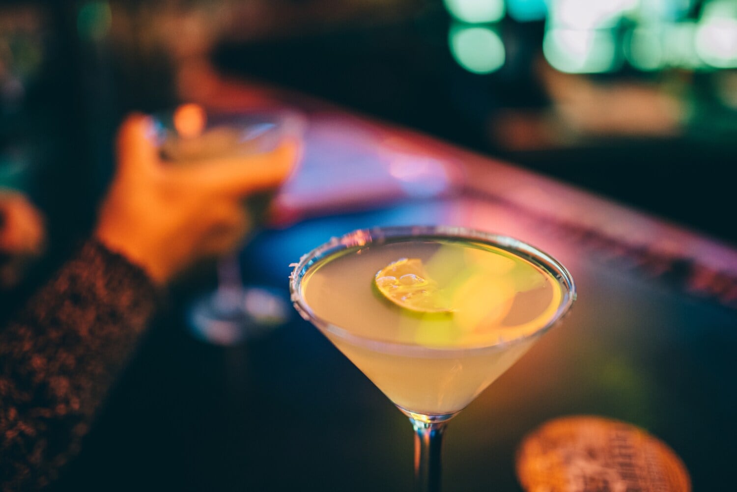 Nahaufnahme eines gelben Cocktails, der an einem Bartresen steht Nahaufnahme eines gelben Cocktails, der an einem Bartresen steht