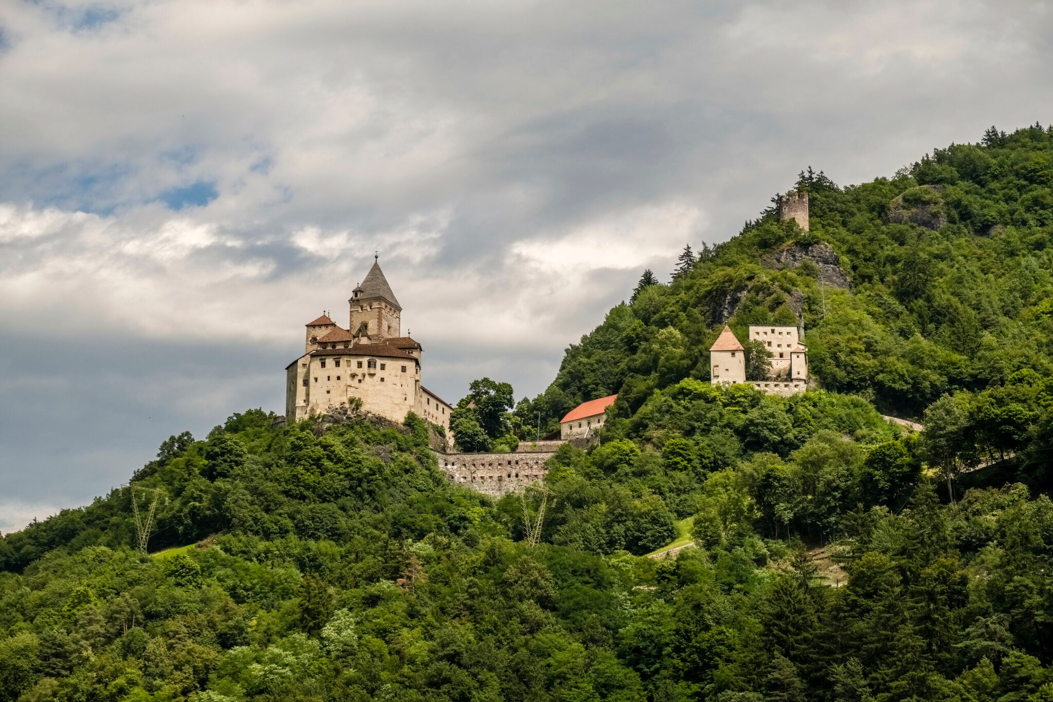 Das Schloss von Bergsteiger Reinhold Messner, das mitten im Grünen auf einem Berg steht.