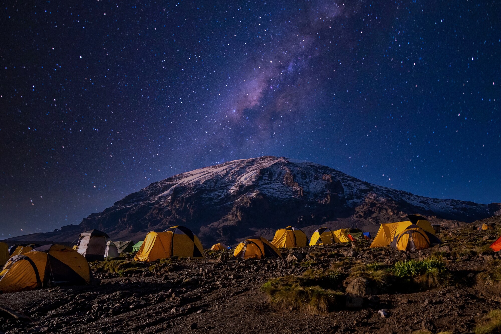 Gelbe Zelte auf einem Berggipfel unter Sternenhimmel bei Nacht Gelbe Zelte auf einem Berggipfel unter Sternenhimmel bei Nacht