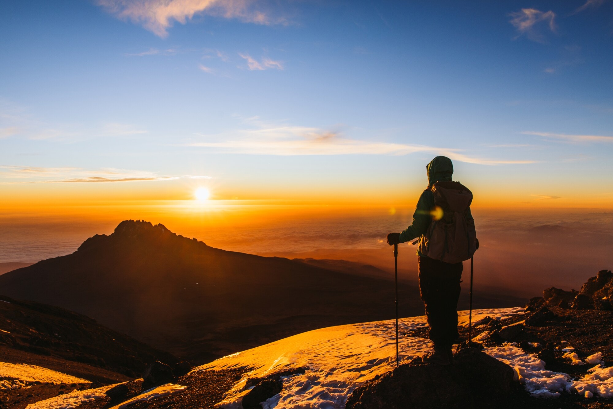 Eine Wanderin blickt vom Gipfel des Kilimandscharo in den Sonnenaufgang Eine Wanderin blickt vom Gipfel des Kilimandscharo in den Sonnenaufgang