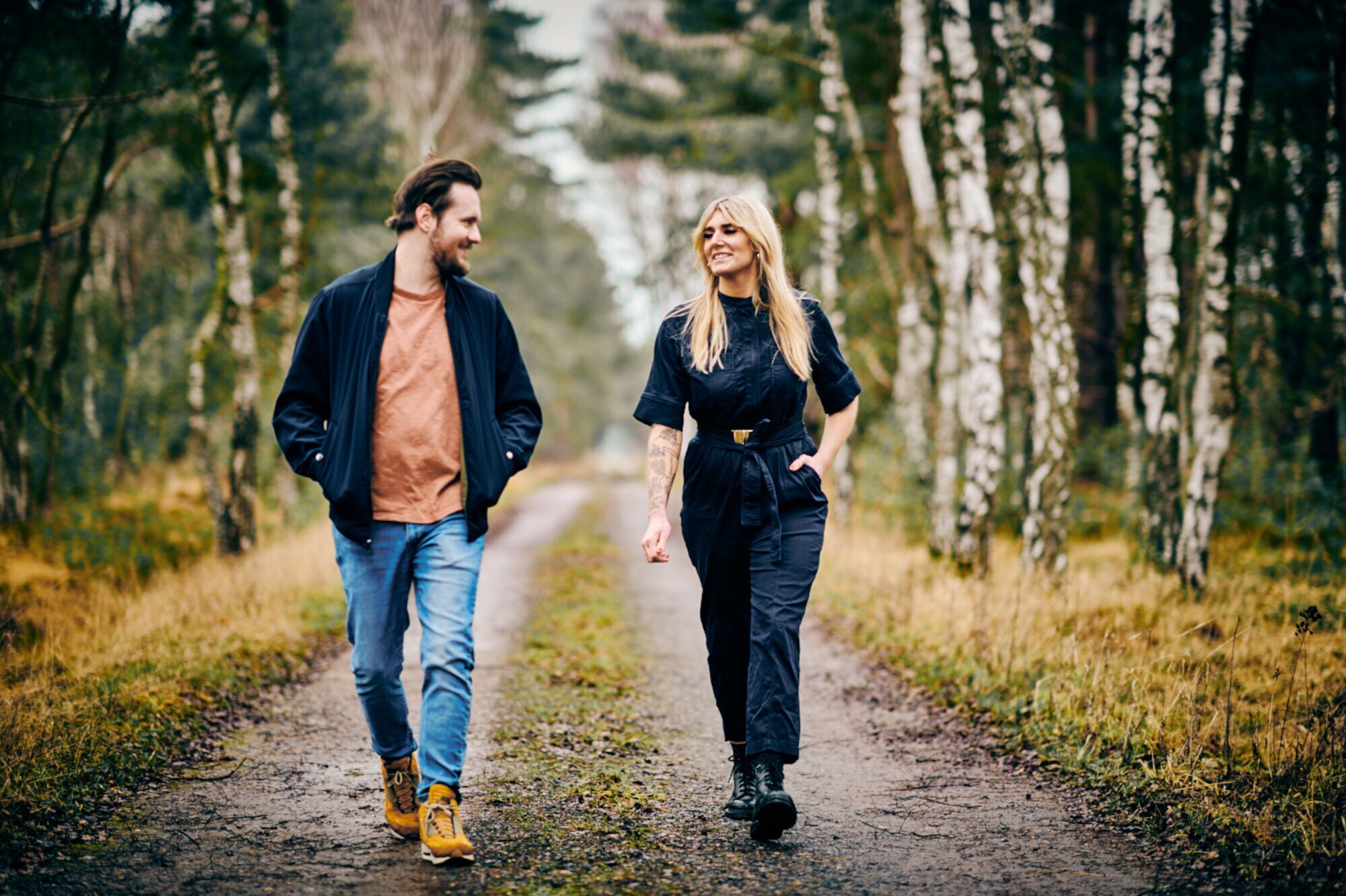 Tony Hohlfeld und Mona Schrader laufen über einen von Birken gesäumten Waldweg