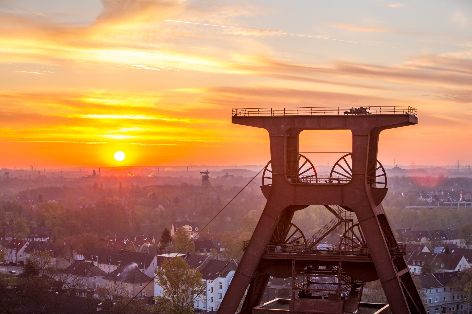Blick auf Doppelbock-Fördergerüst vom Dach der Kohlenwäsche des UNESCO-Welterbes Zollverein beim Sonnenaufgang