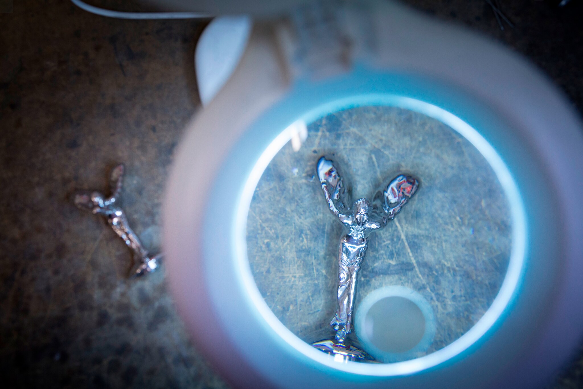 Detailaufnahme eine Kühlerfigur unter einer Lupe