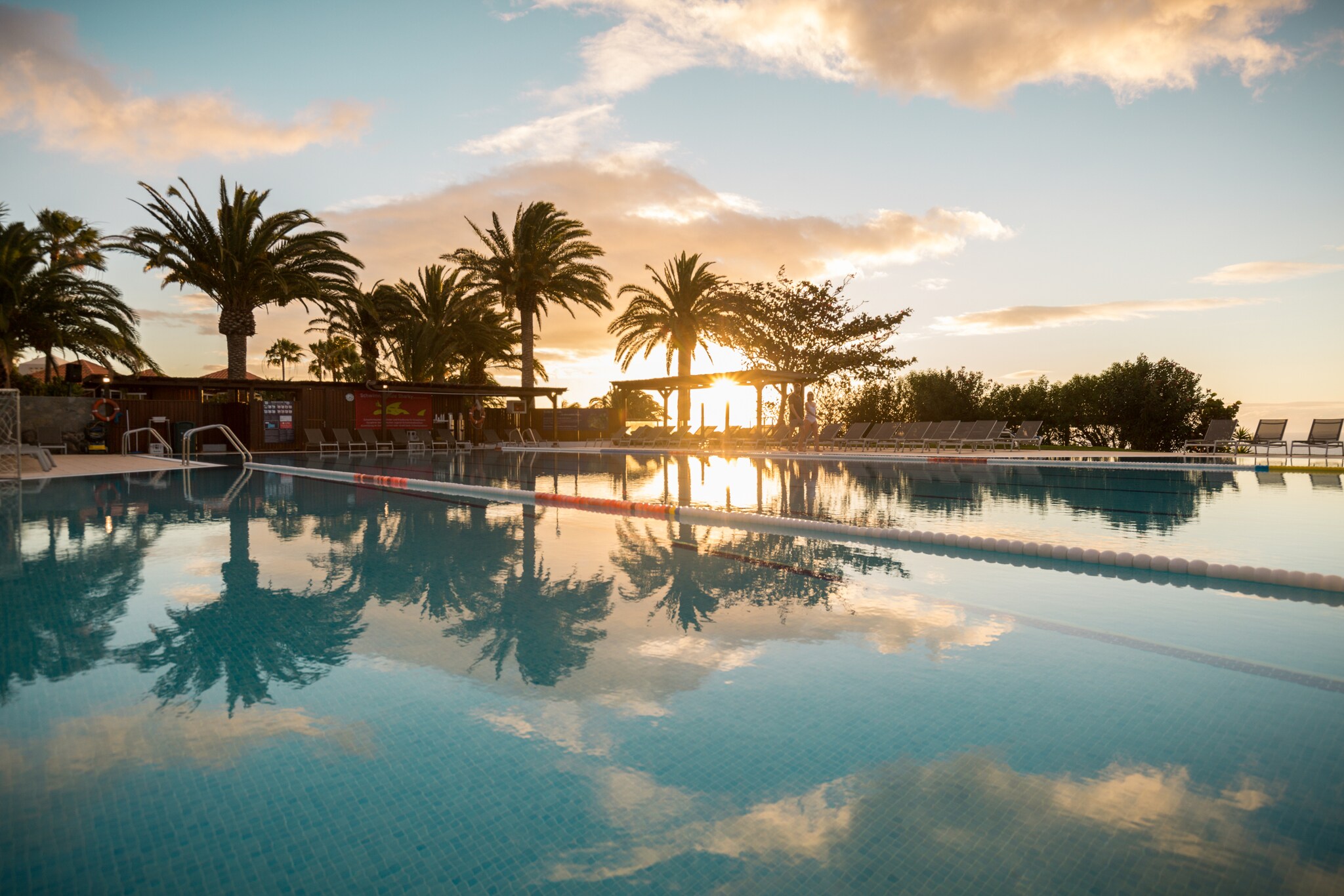 Ein großer Außenpool in einer Hotelanlage am Meer bei Sonnenuntergang Ein großer Außenpool in einer Hotelanlage am Meer bei Sonnenuntergang