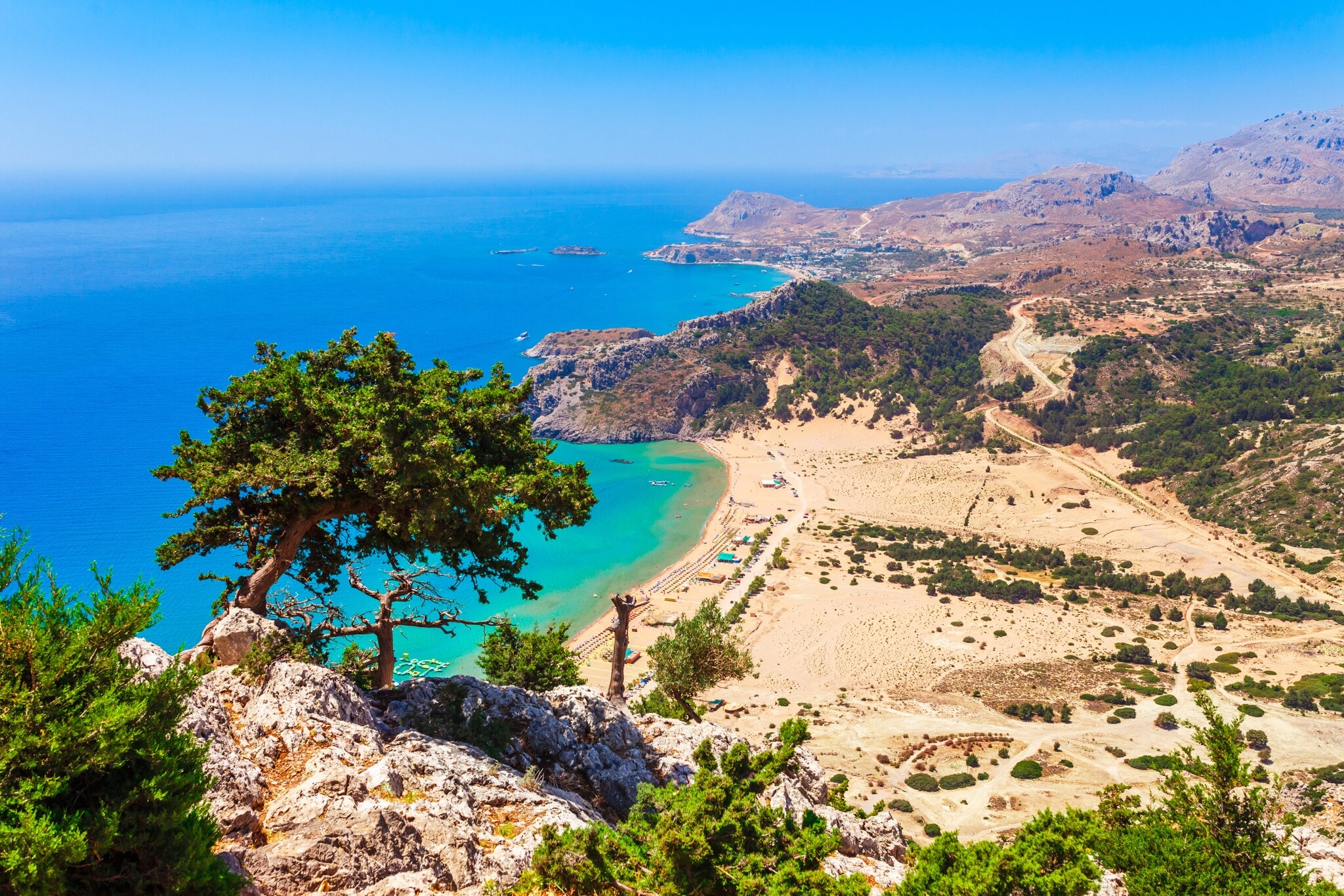 Blick von einem Berg auf einen Strand und hellblaues Wasser Blick von einem Berg auf einen Strand und hellblaues Wasser