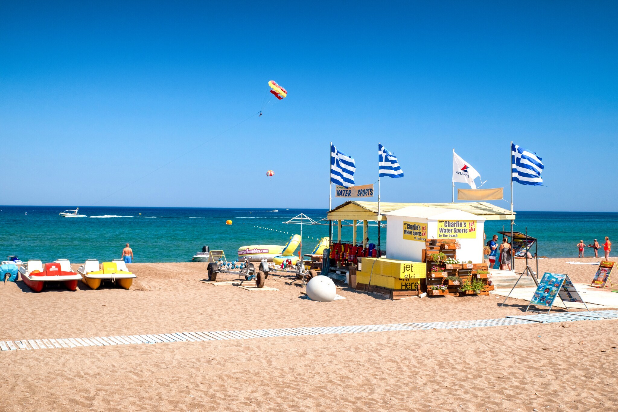 Strandhütte mit blauweißen Fahnen an einem Strand mit trükisfarbenem Meer Strandhütte mit blauweißen Fahnen an einem Strand mit trükisfarbenem Meer
