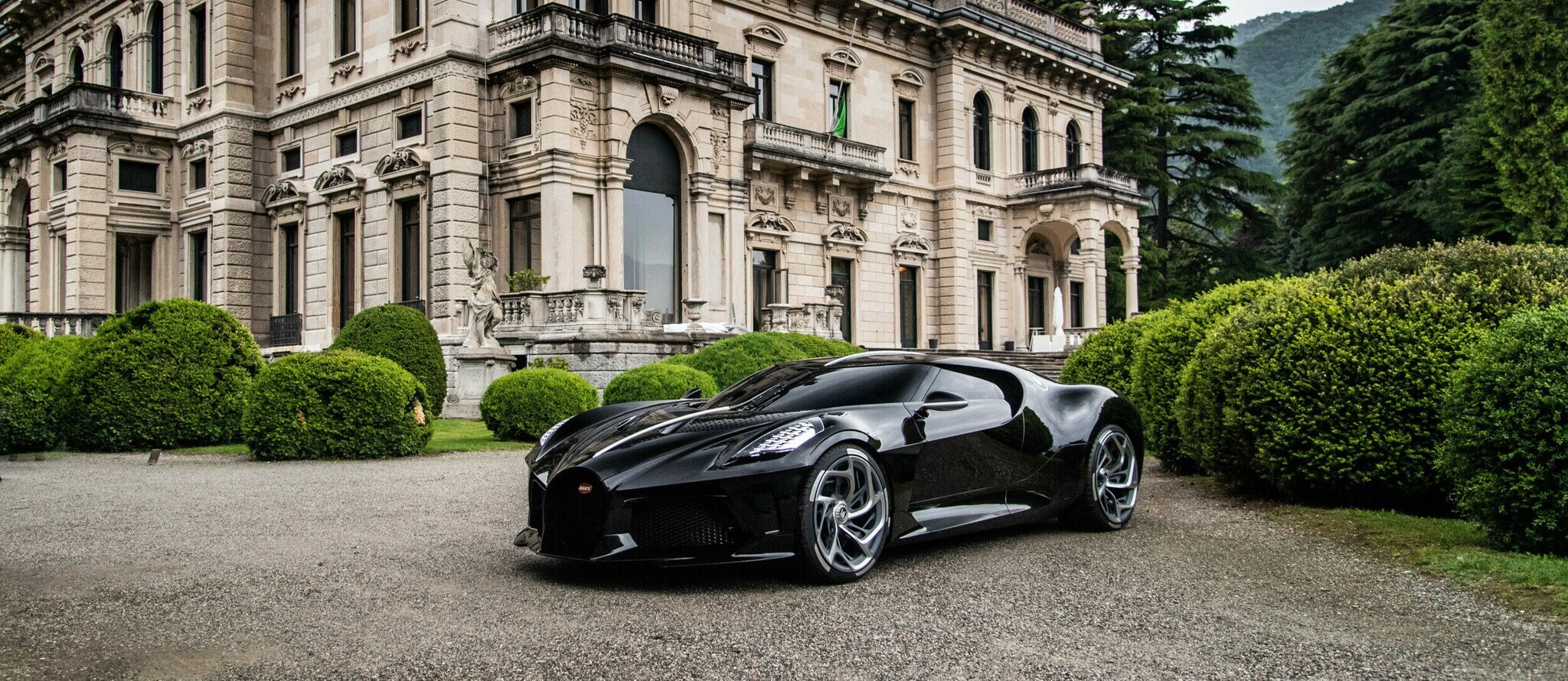 Ein schwarzer Bugatti vor einem alten Schloss.