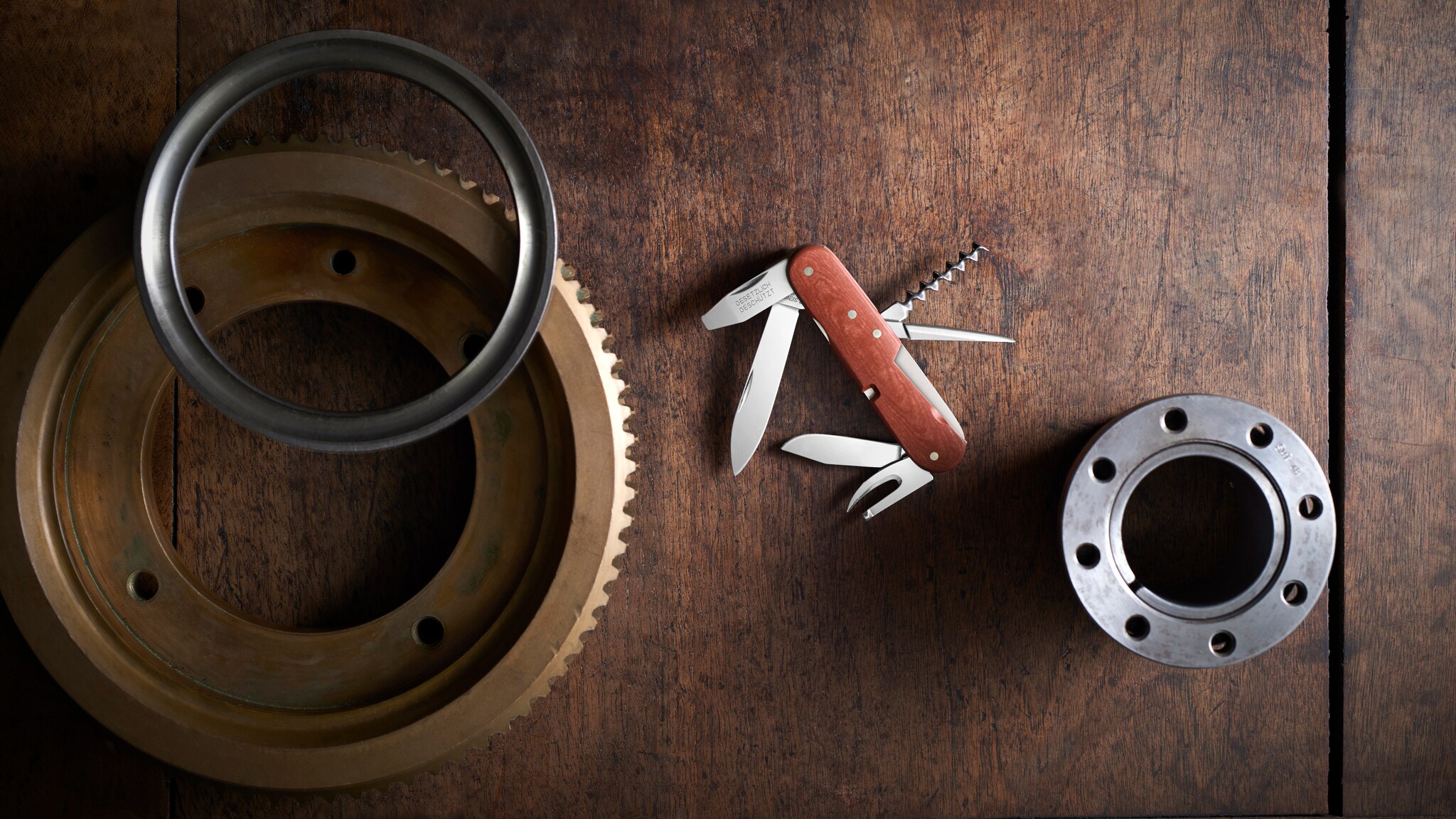 Ein aufgeklapptes Schweizer Taschenmesser mit Holzschale auf einem Holztisch