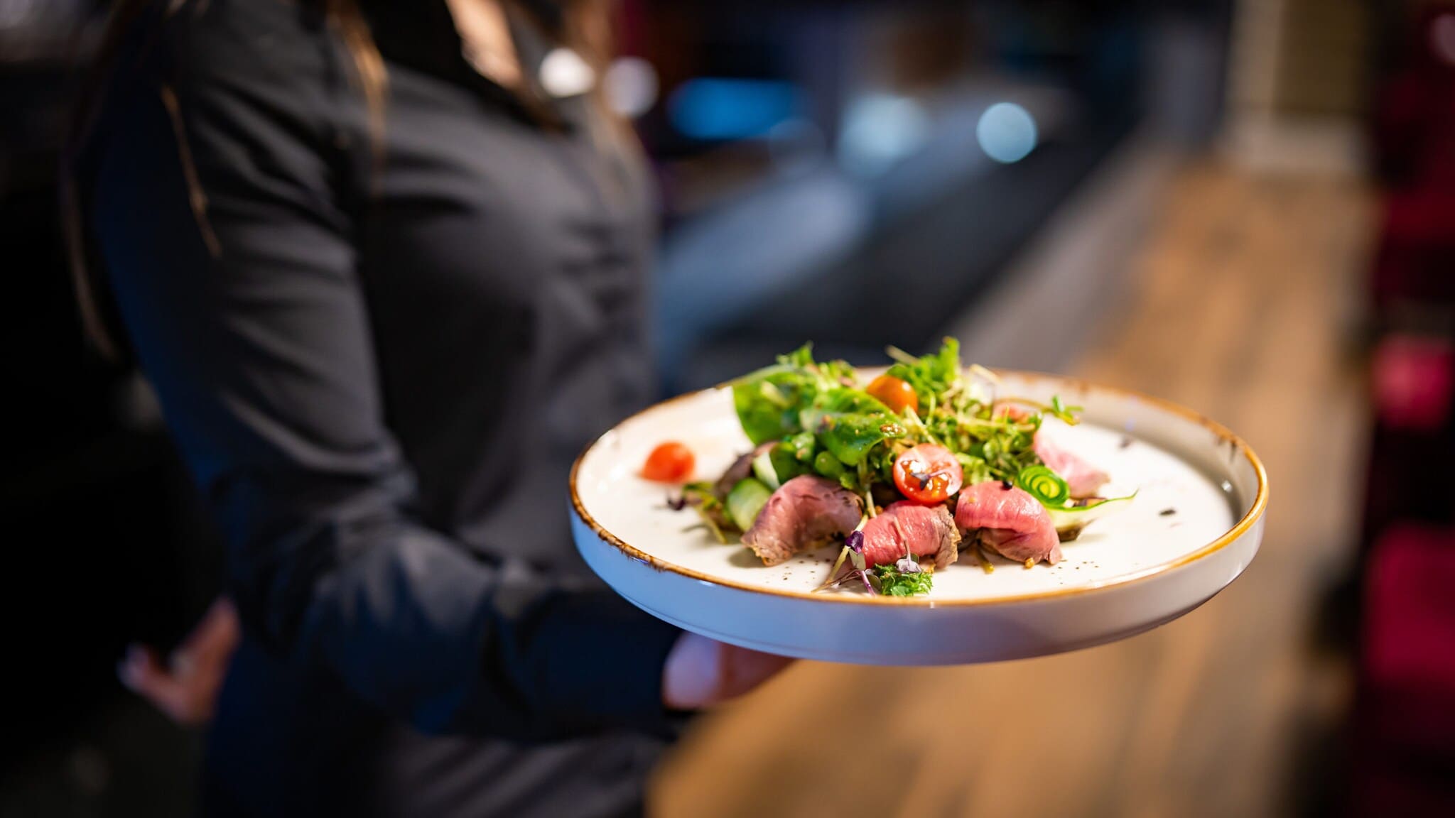 Eine Person hält einhändig einen Teller, auf dem ein Salat angerichtet ist. Eine Person hält einhändig einen Teller, auf dem ein Salat angerichtet ist.