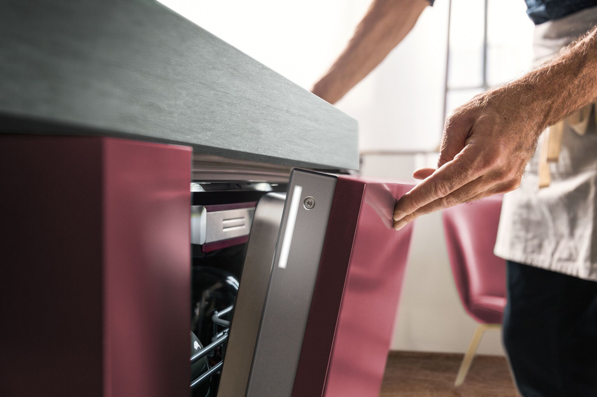 Ein Mann schließt einen weinroten Geschirrspüler