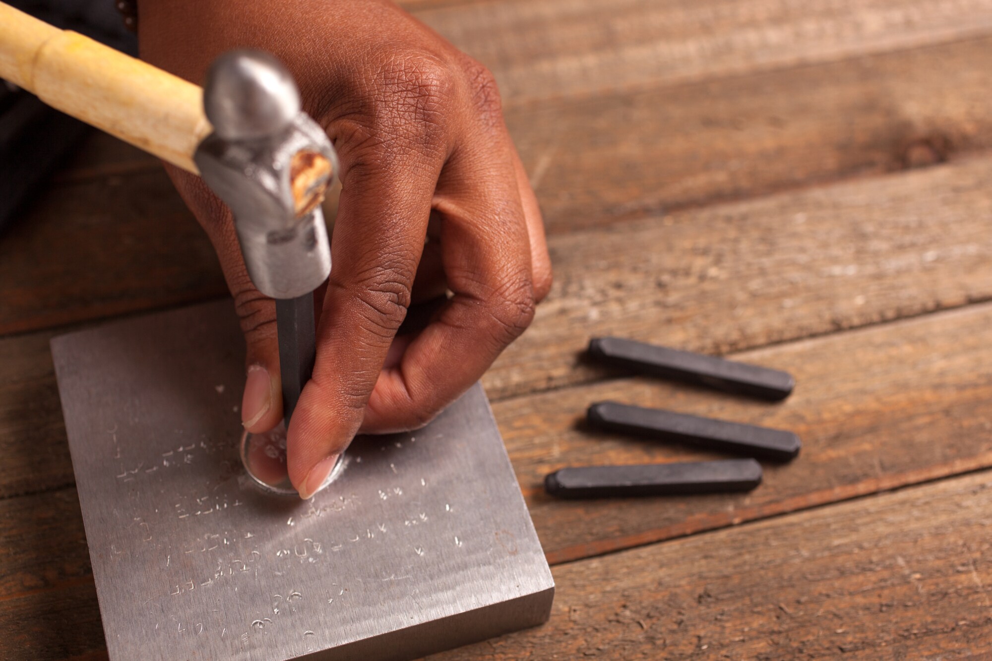 Eine Person stempelt etwas auf ein Stück Metall Eine Person stempelt etwas auf ein Stück Metall