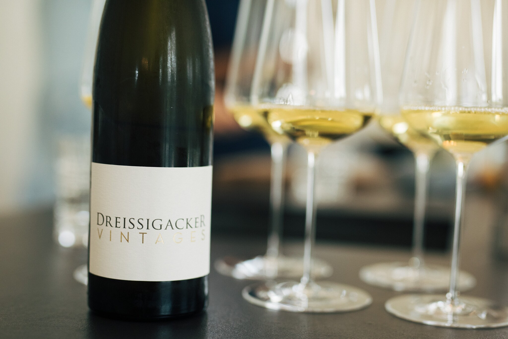 Eine Weinflasche des Labels Dreissigacker Vintage neben gefüllten Weißweingläsern