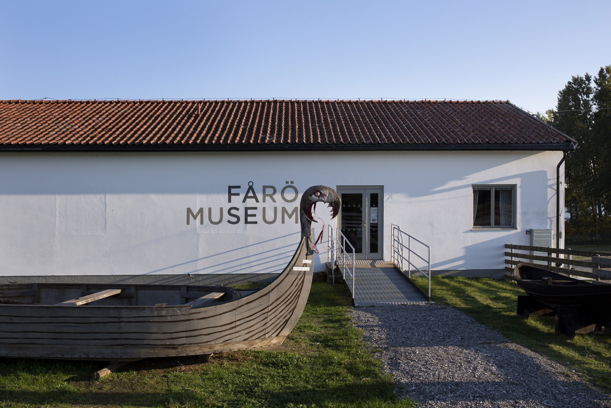 Außenansicht des Farö-Museums, vor dem ein Holzschiff steht. Außenansicht des Farö-Museums, vor dem ein Holzschiff steht.