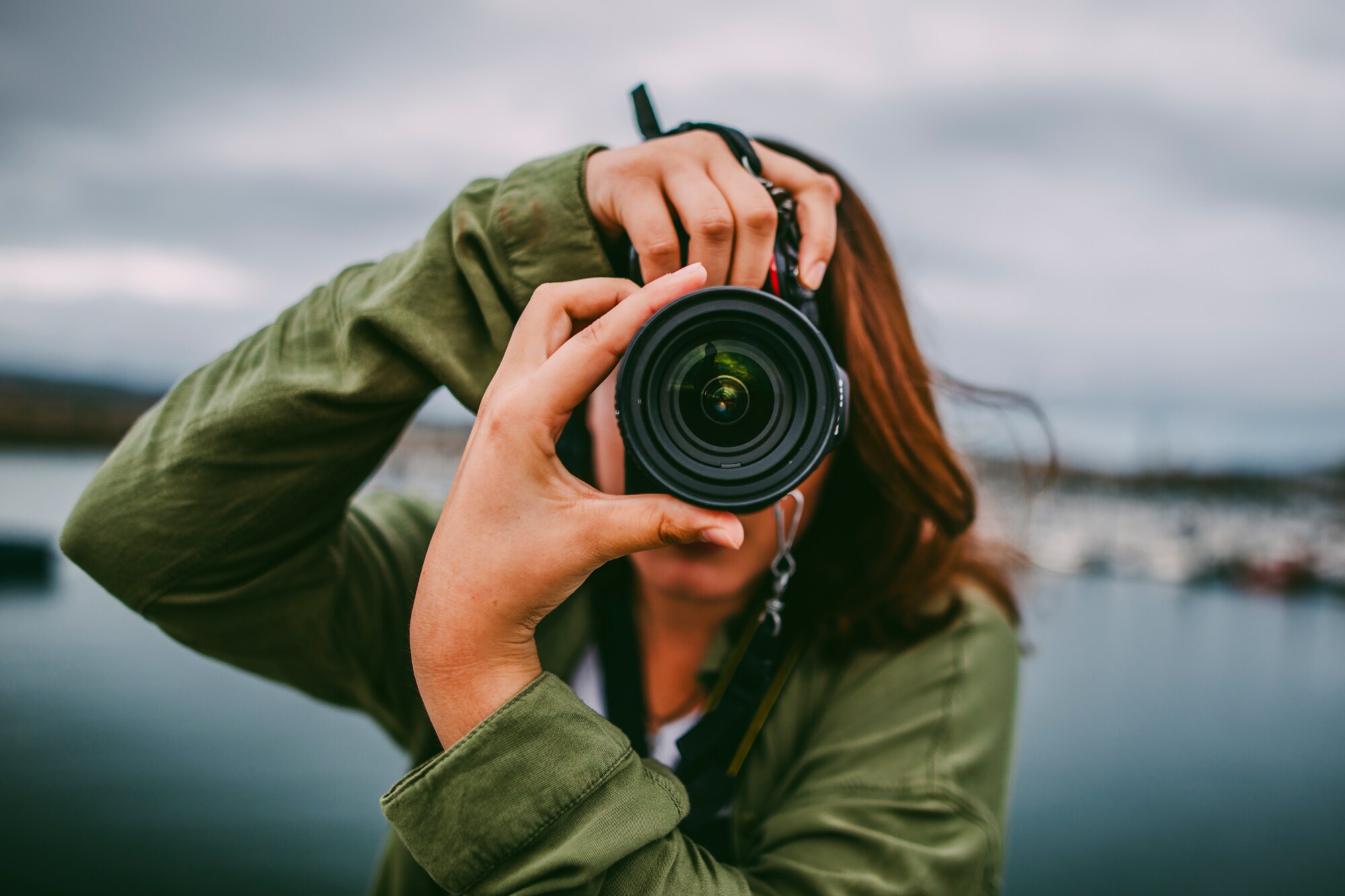 Nahaufnahme einer Person, die durch ihre Kamera auf den Fotografierenden blickt Nahaufnahme einer Person, die durch ihre Kamera auf den Fotografierenden blickt