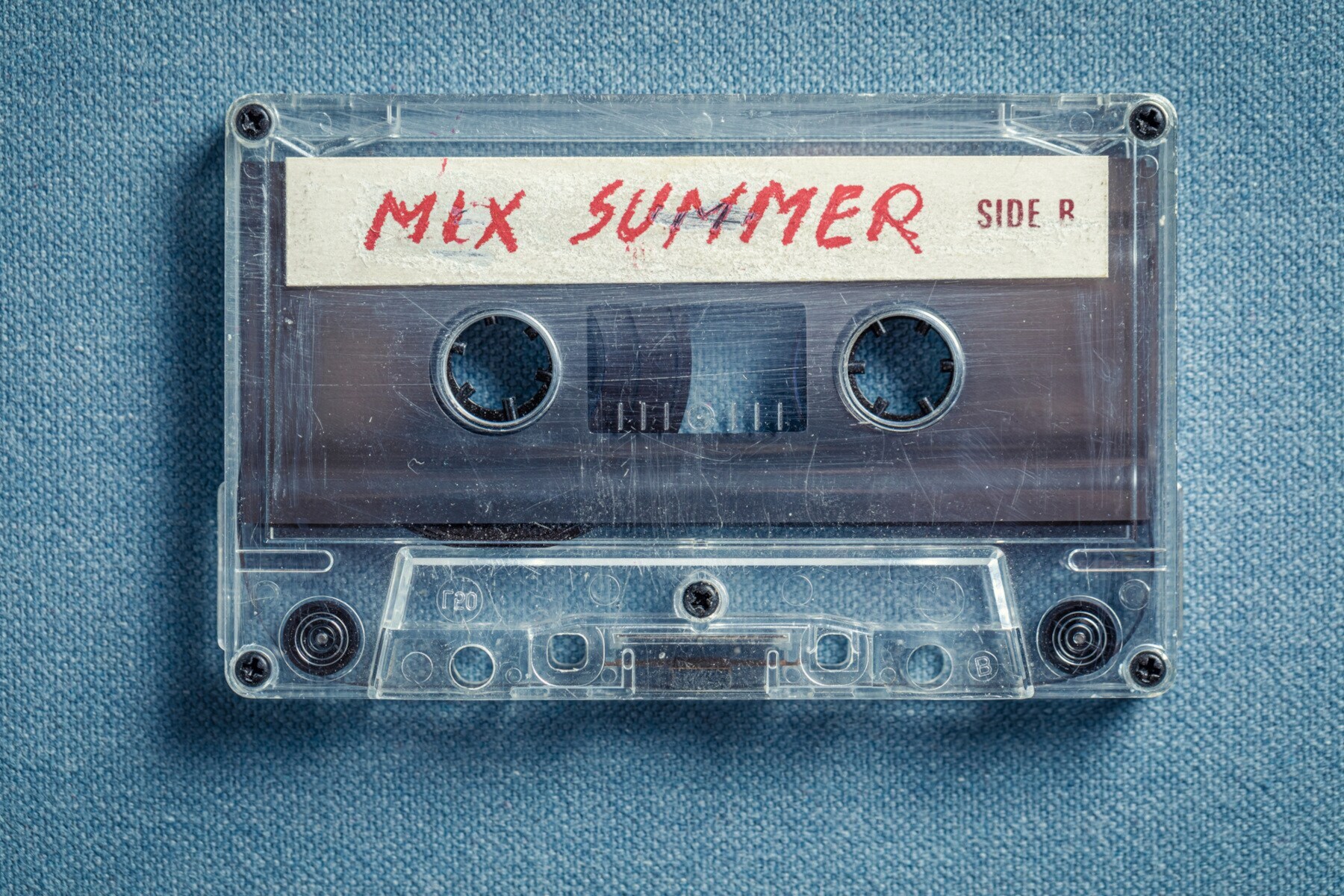 Nahaufnahme einer Kassette mit der Aufschrift „Mix Summer” auf blauem Stoff