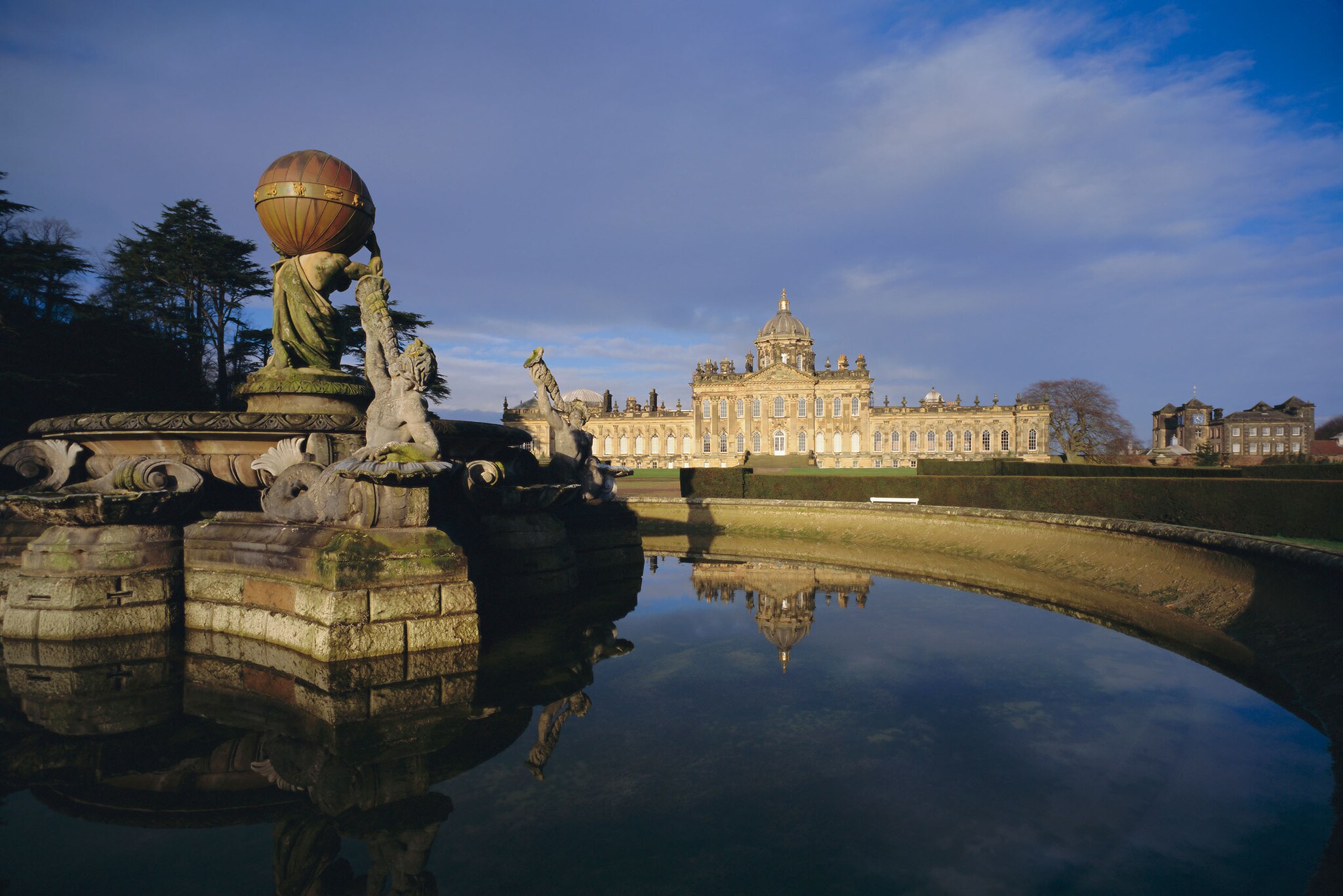 Außenansicht von Castle Howard mit Springbrunnen im Vordergrund bei Abenddämmerung.