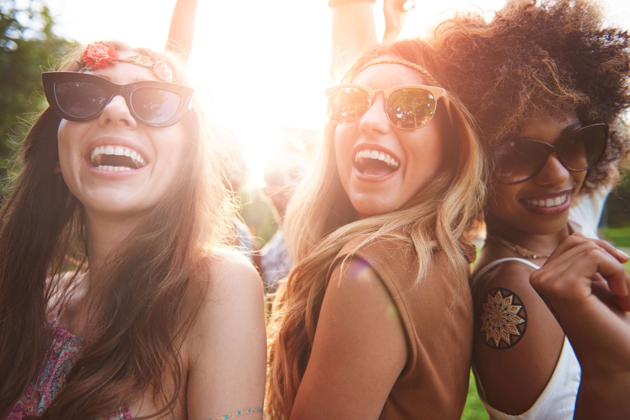 Drei lächelnde und posierende Personen mit Sonnenbrille und Tops an. Drei lächelnde und posierende Personen mit Sonnenbrille und Tops an.