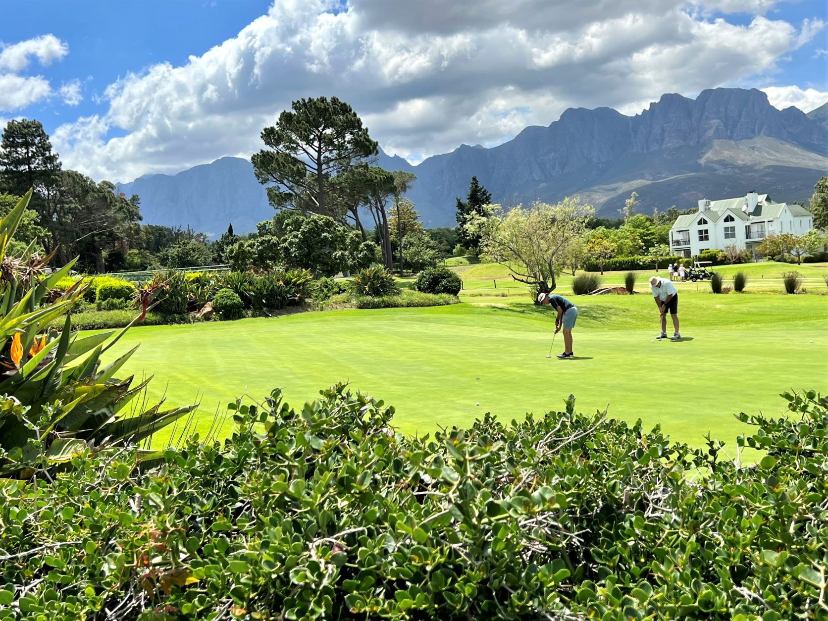 Zwei Personen spielen auf einer gepflegten Grünanlage Golf.