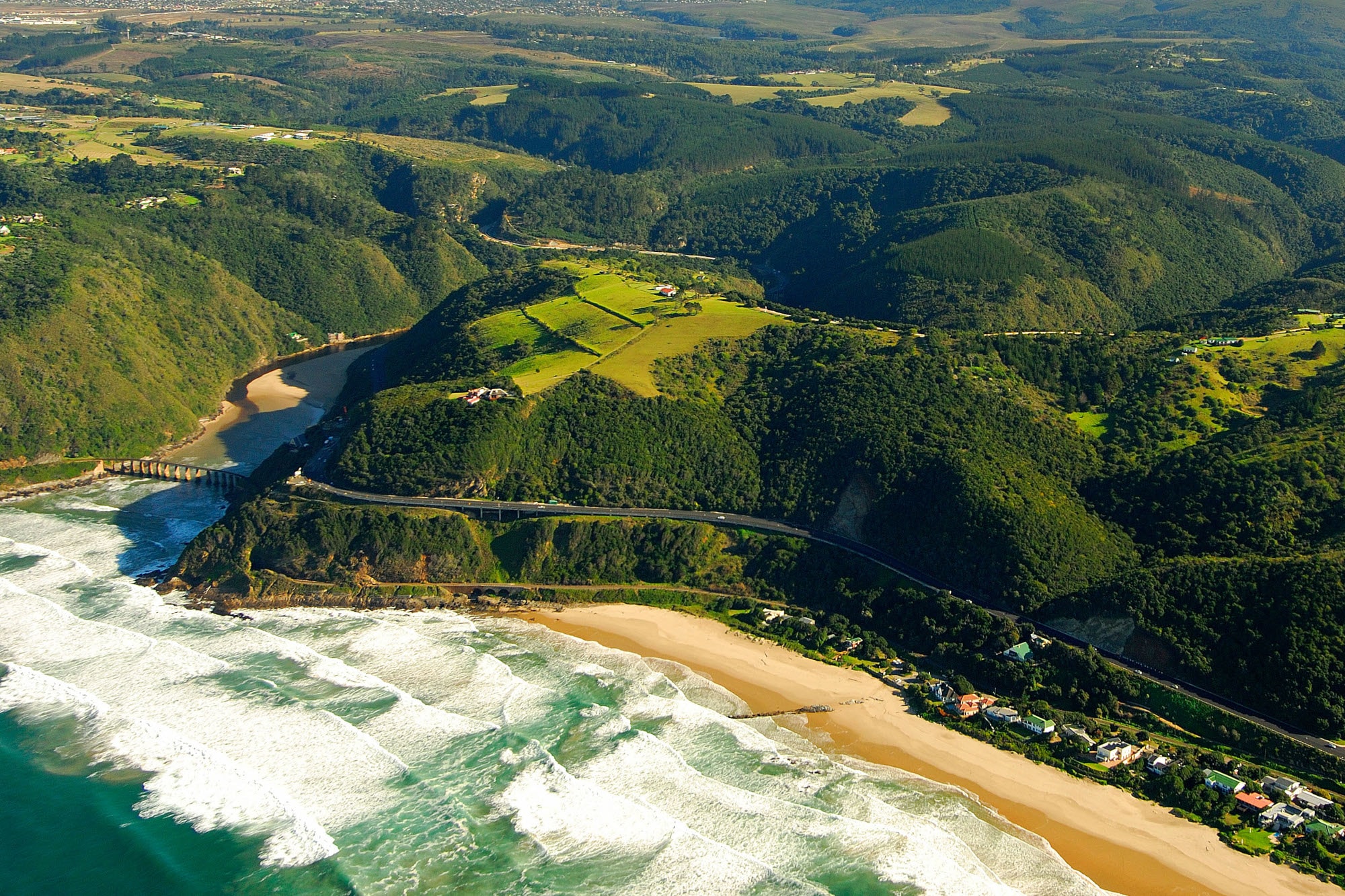 Luftaufnahme der Garden Route, die durch grüne Wälder entlang der Küste führt Luftaufnahme der Garden Route, die durch grüne Wälder entlang der Küste führt