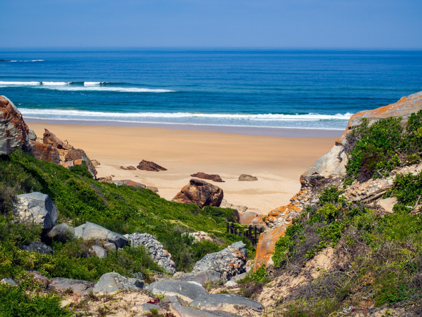 Blick von einem Felsen auf einen Sandstrand in einer menschenleeren Bucht, umgeben von wider Natur Blick von einem Felsen auf einen Sandstrand in einer menschenleeren Bucht, umgeben von wider Natur