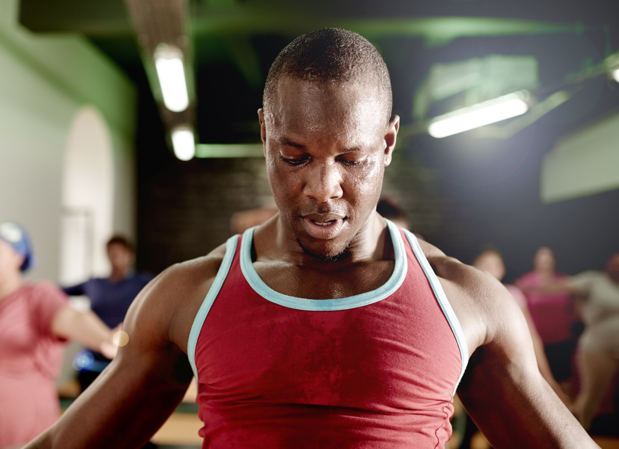 Eine schwitzende Person treibt zusammen mit anderen Personen im Studio intensiv Sport
