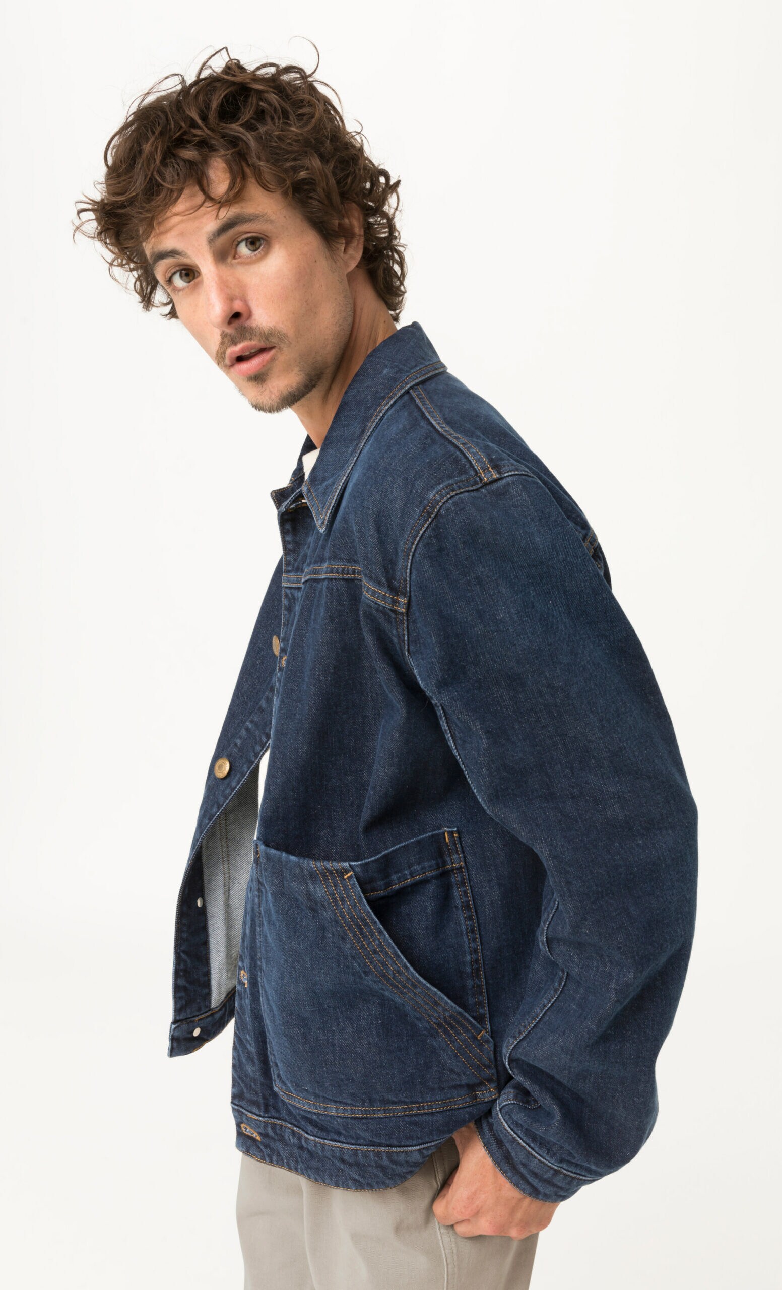 Model in Jeansjacke aus dunkelblauem Denim mit schrägen Taschen, Studioaufnahme Model in Jeansjacke aus dunkelblauem Denim mit schrägen Taschen, Studioaufnahme
