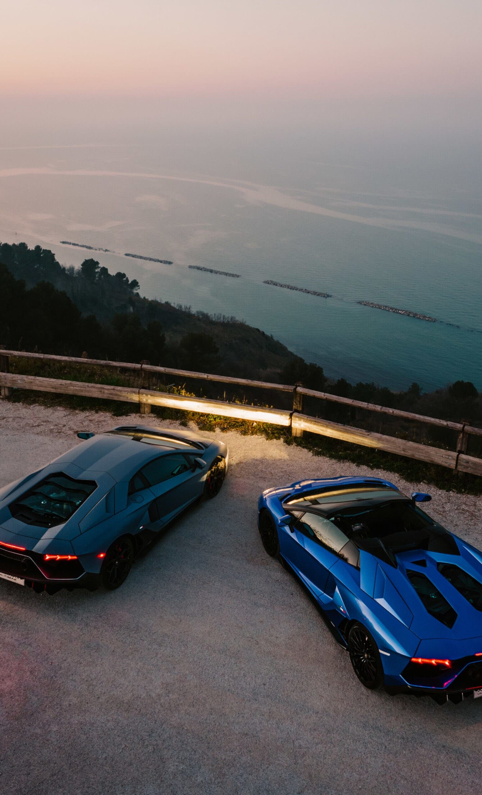 Zwei Sportwagen von oben auf einer Straße am Meer Zwei Sportwagen von oben auf einer Straße am Meer