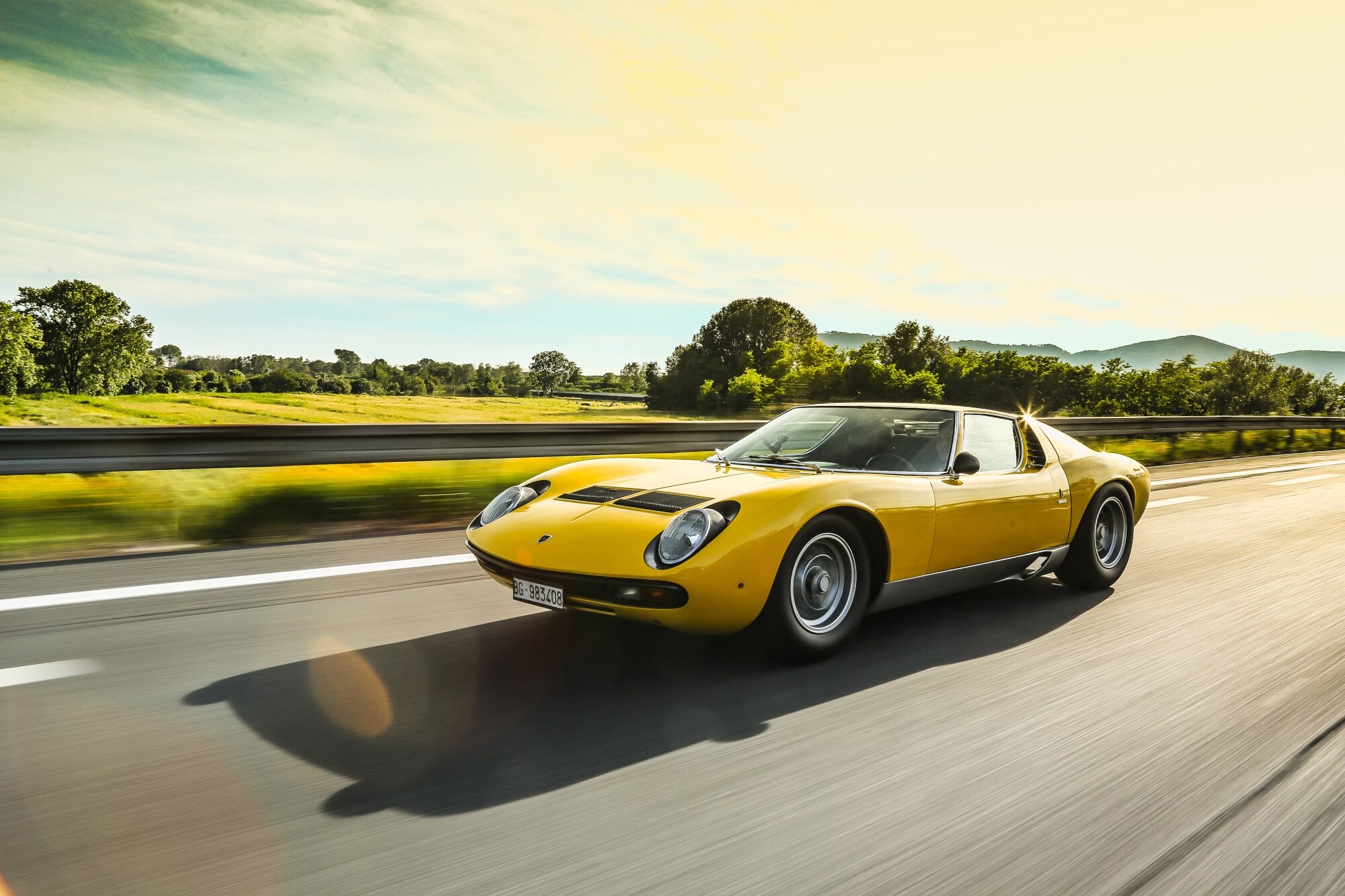 Ein gelber Sportwagen auf einer sommerlichen Straße Ein gelber Sportwagen auf einer sommerlichen Straße