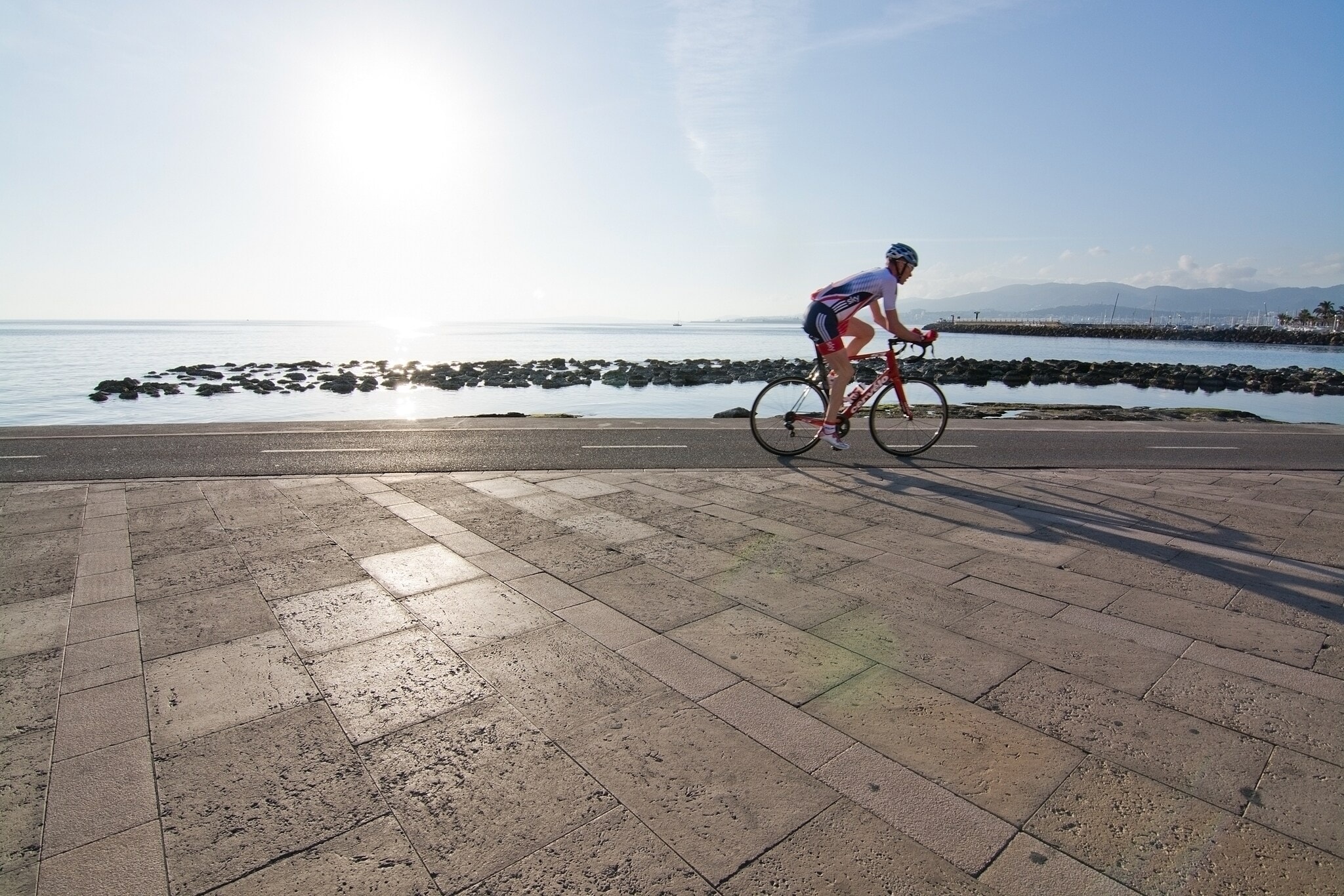 Mann auf Rennrad an Mallorcas Küste, im Vordergrund Pflaster Mann auf Rennrad an Mallorcas Küste, im Vordergrund Pflaster