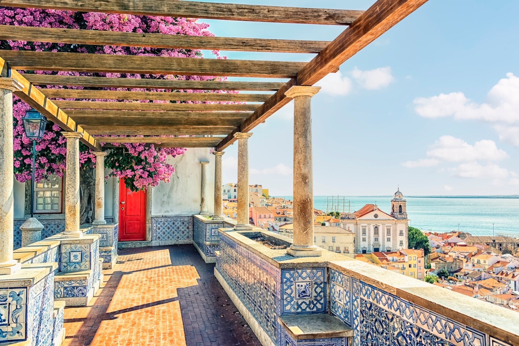 Terrasse mit portugiesischen Kacheln und Bougainvillea mit Blick auf Lissabon am Meer