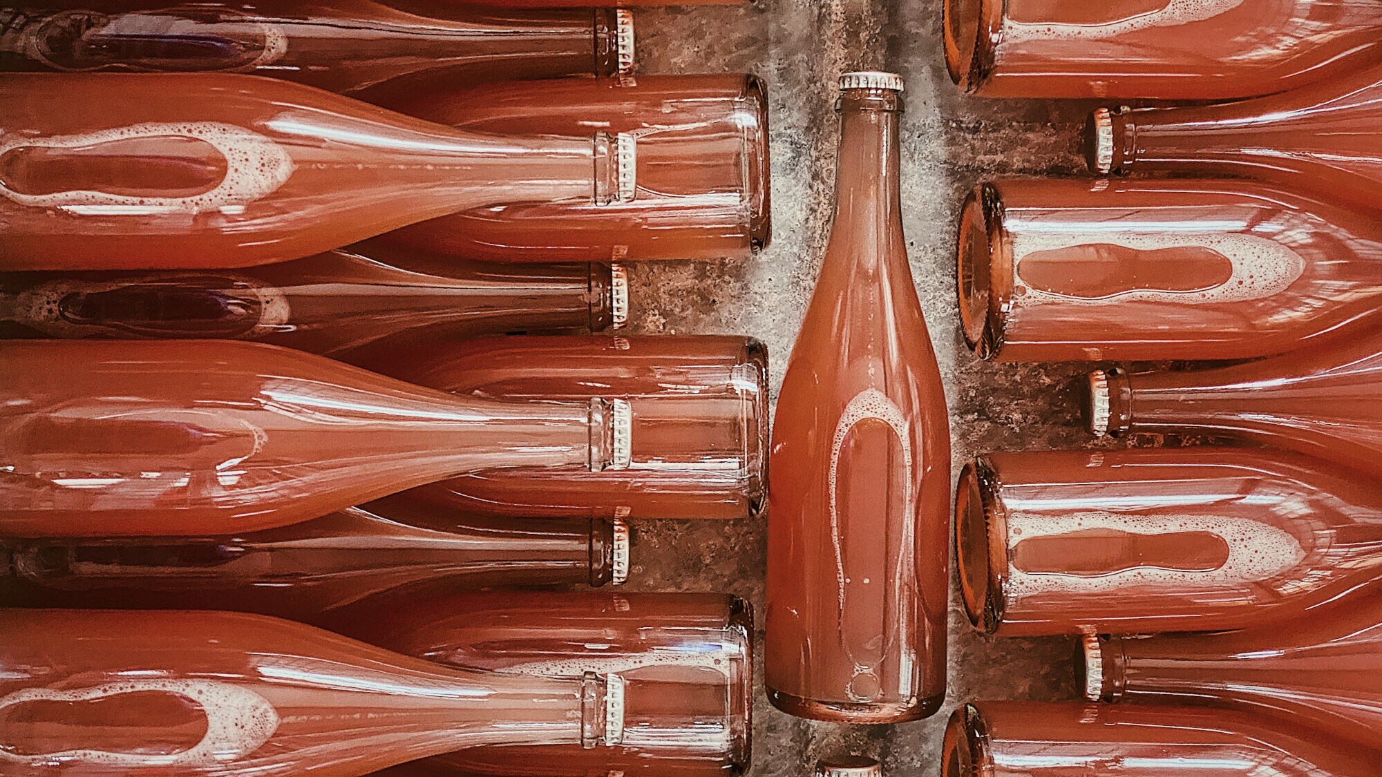 Mehrere Pet Nat Flaschen ohne Label, die in einem Wasserbad liegen