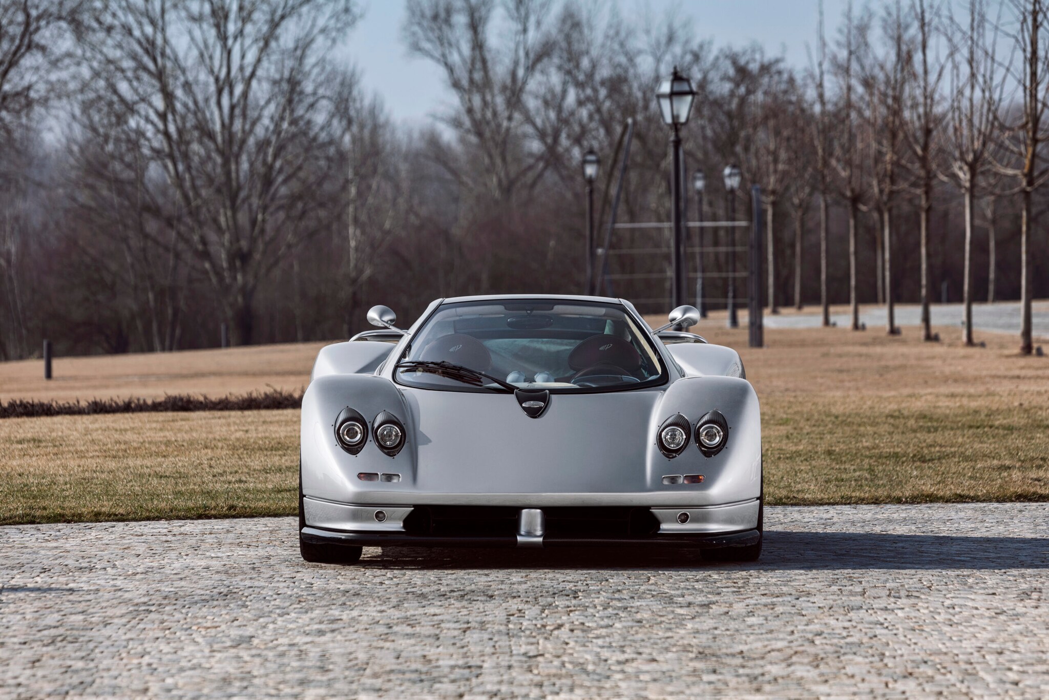 Ein silbergrauer Pagani Zonda C12 steht auf einer gepflasterten Fläche