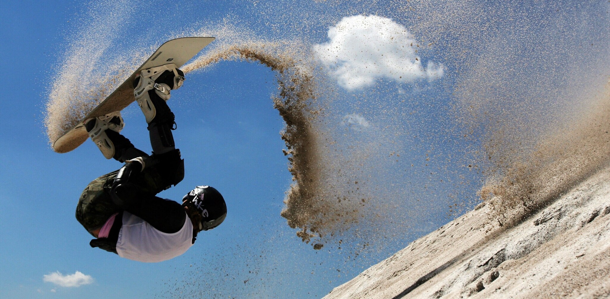 Eine Sandboarderin schlägt einen Salto auf der Sandpiste