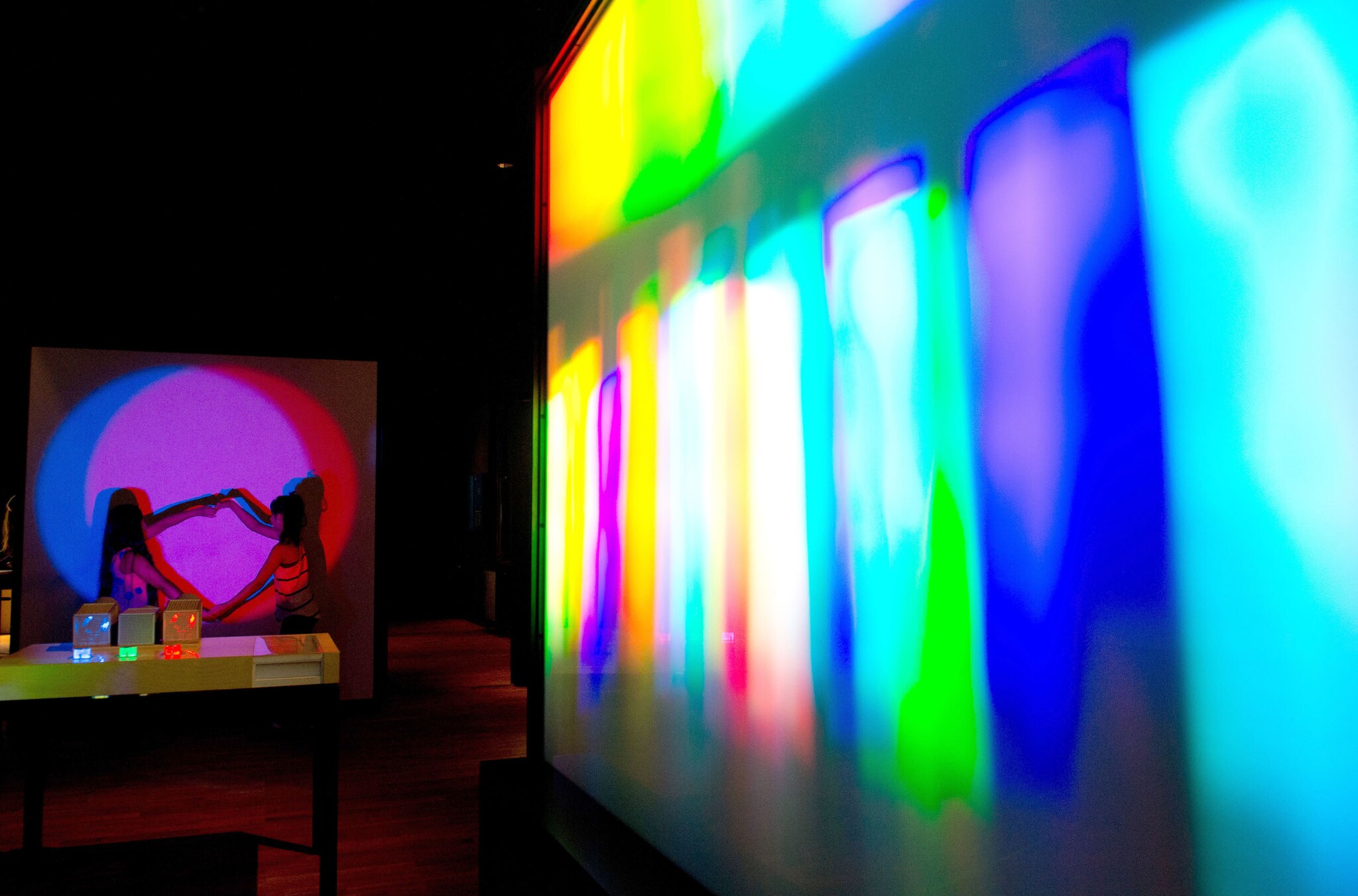 Zwei Kinder experimentieren mit Projektionen von farbigem Licht