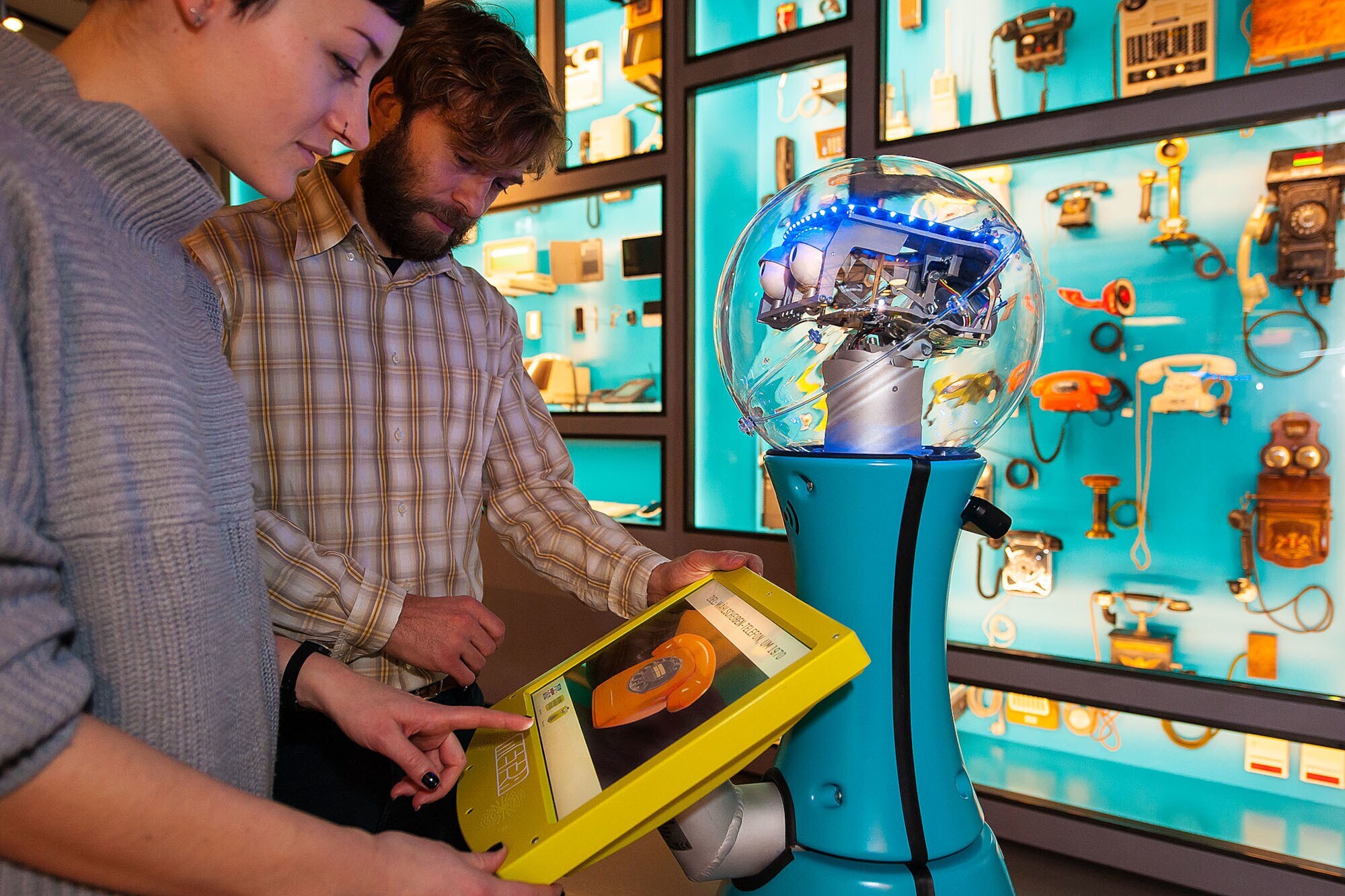 Zwei Personen schauen auf das Display eines Serviceroboters in einer Museumsausstellung