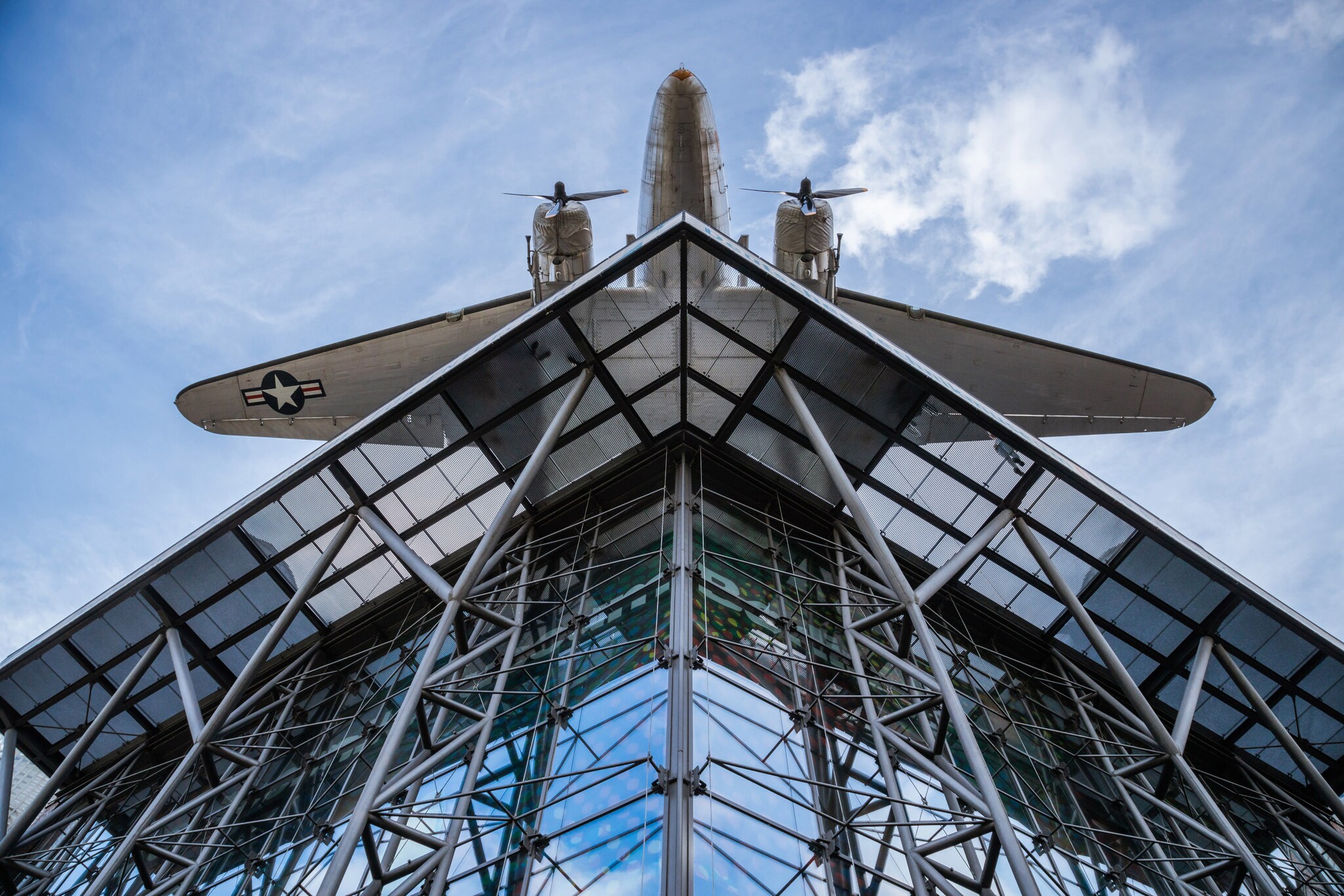 Untersicht eines Flugzeuges auf dem Dach eines modernen Gebäudes mit Glasfassade
