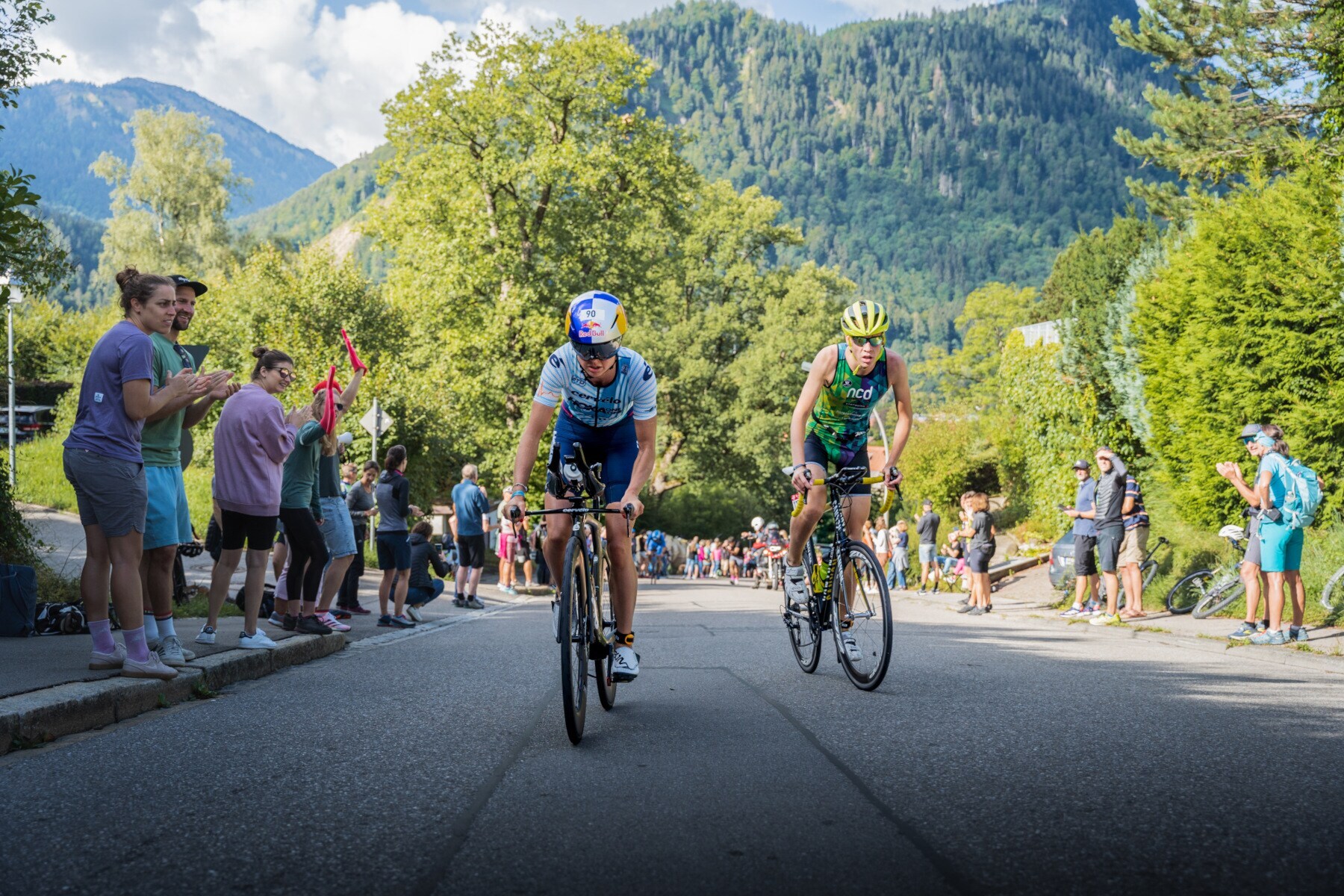 Zwei Personen auf dem Rad fahren auf die Kamera zu und werden von mehreren Menschen angefeuert Zwei Personen auf dem Rad fahren auf die Kamera zu und werden von mehreren Menschen angefeuert