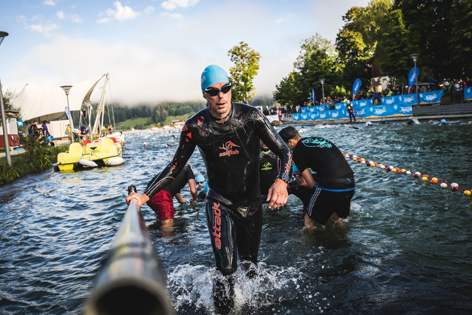 Eine Person im Neoprenanzug steigt aus einer Wasserquelle heraus Eine Person im Neoprenanzug steigt aus einer Wasserquelle heraus