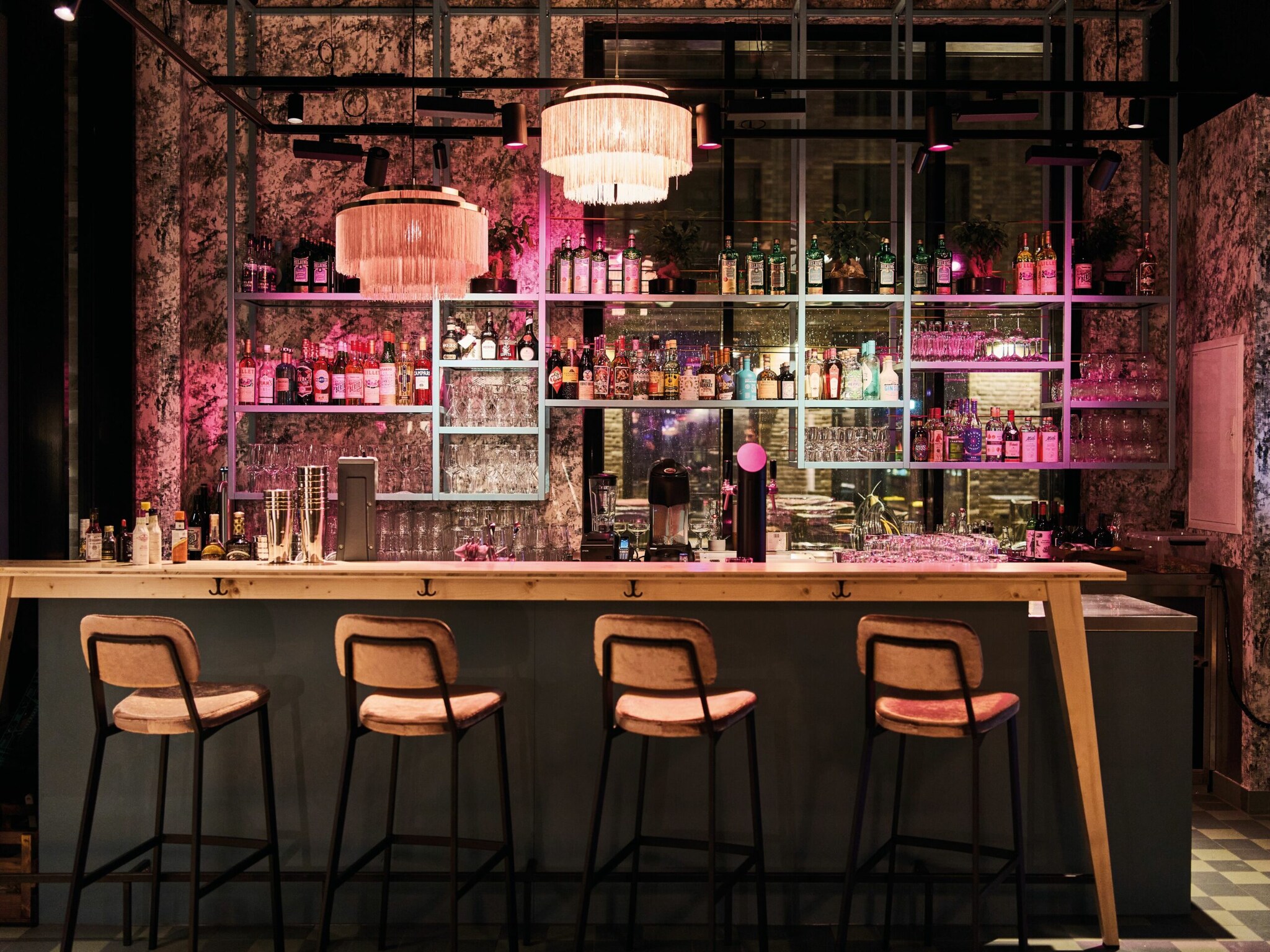 Bunt beleuchtete Bar mit Barhockern und Hängelampen im Urban Nature Hotel St. Peter Ording