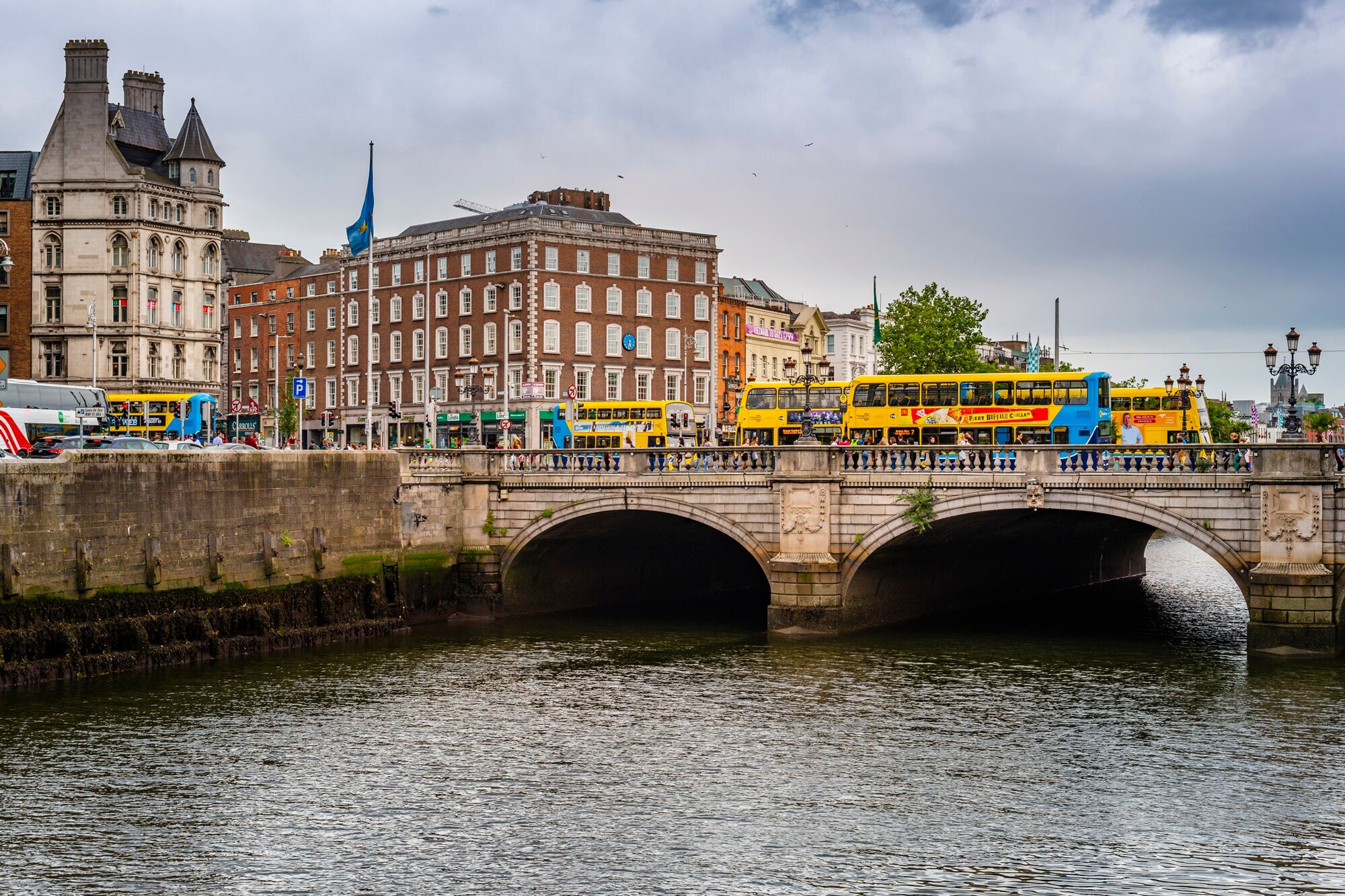 Über eine Brücke, die über den Liffey River führt, fahren mehrere Touristenbusse