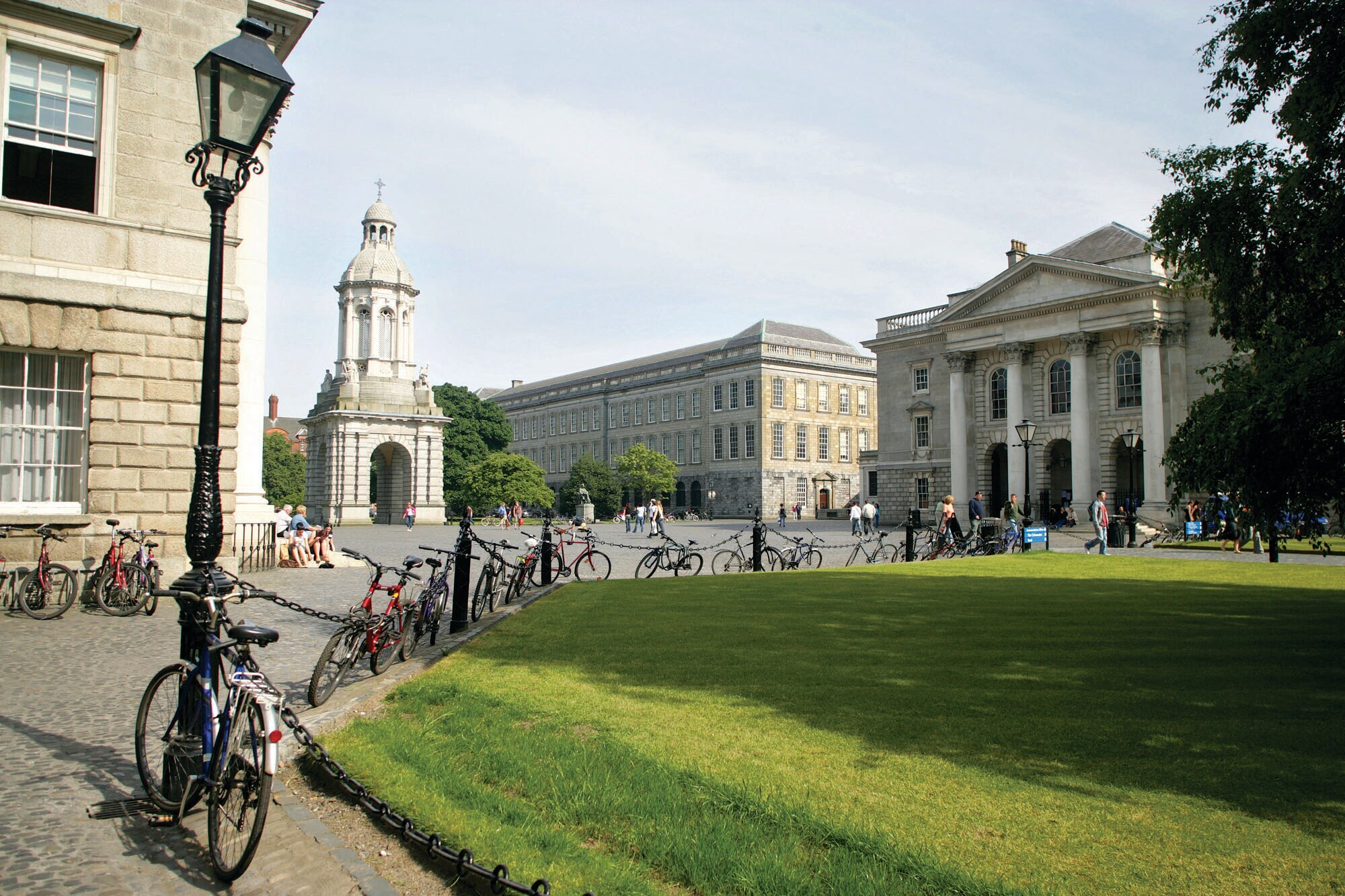 Das Trinity College mit einer Grünanlage im Vordergrund und mehreren abgestellten Fahrrädern